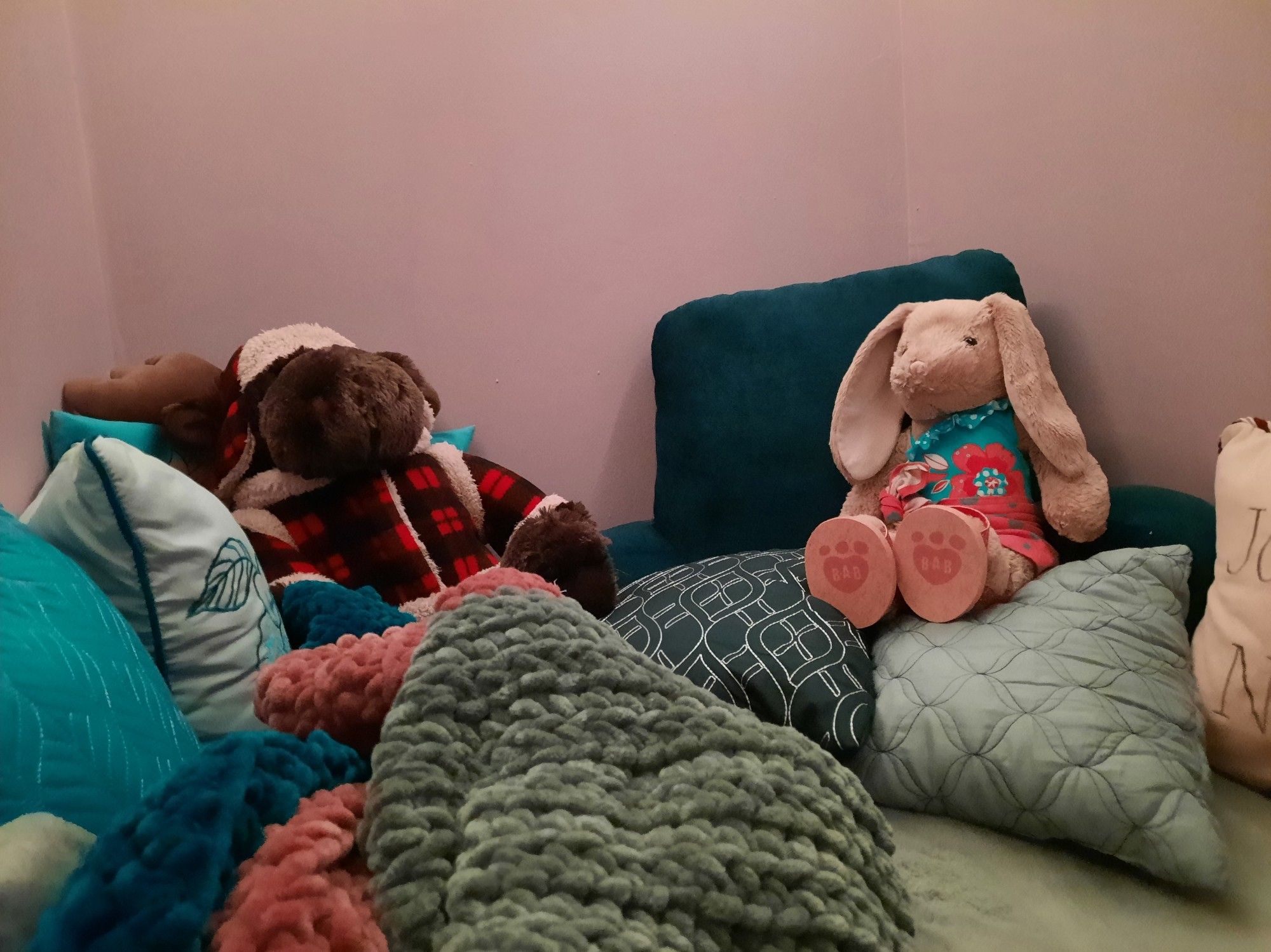 Tuk the moose and Heïdi the rabbit sitting with a plethera of pillows and a super fluffy blanket