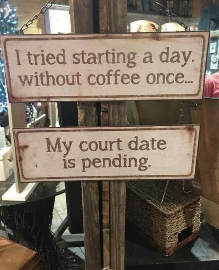 Two white signs nailed to a wooden post, one above the other. The top one reads ‘I tried starting a day without coffee once…’ the bottom one reads ‘my court date is pending’