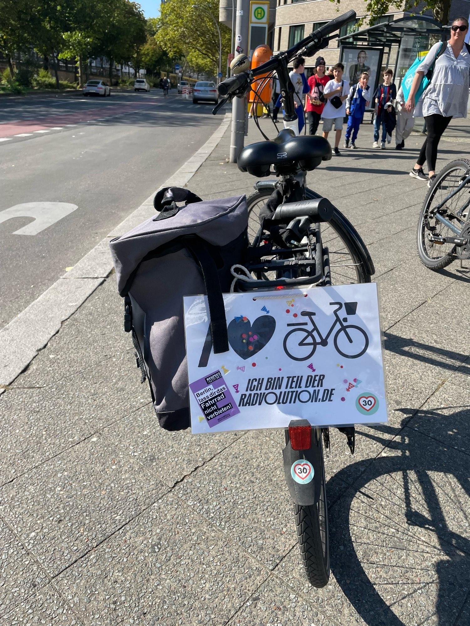 Ein Dahrrad von hinten fotografiert. Am Gepäckträger ein Schild „Ich bin Teil der Radvolution“ Stickers mit Tempo 30 und „Berlin, lass dir das Fahrrad nicht verbieten“