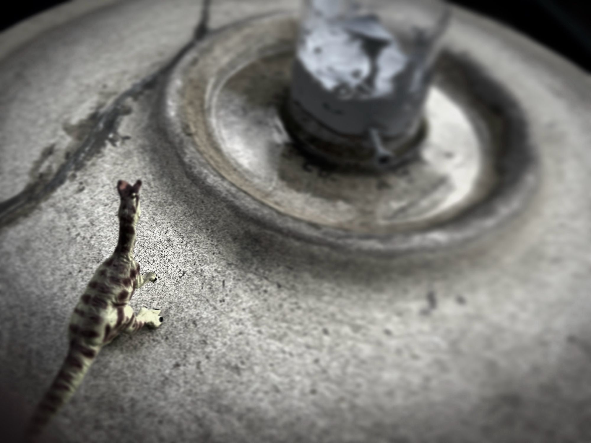 A nearly greyscale image of a little Dilophosaurus standing on the edge of a downed UFO.