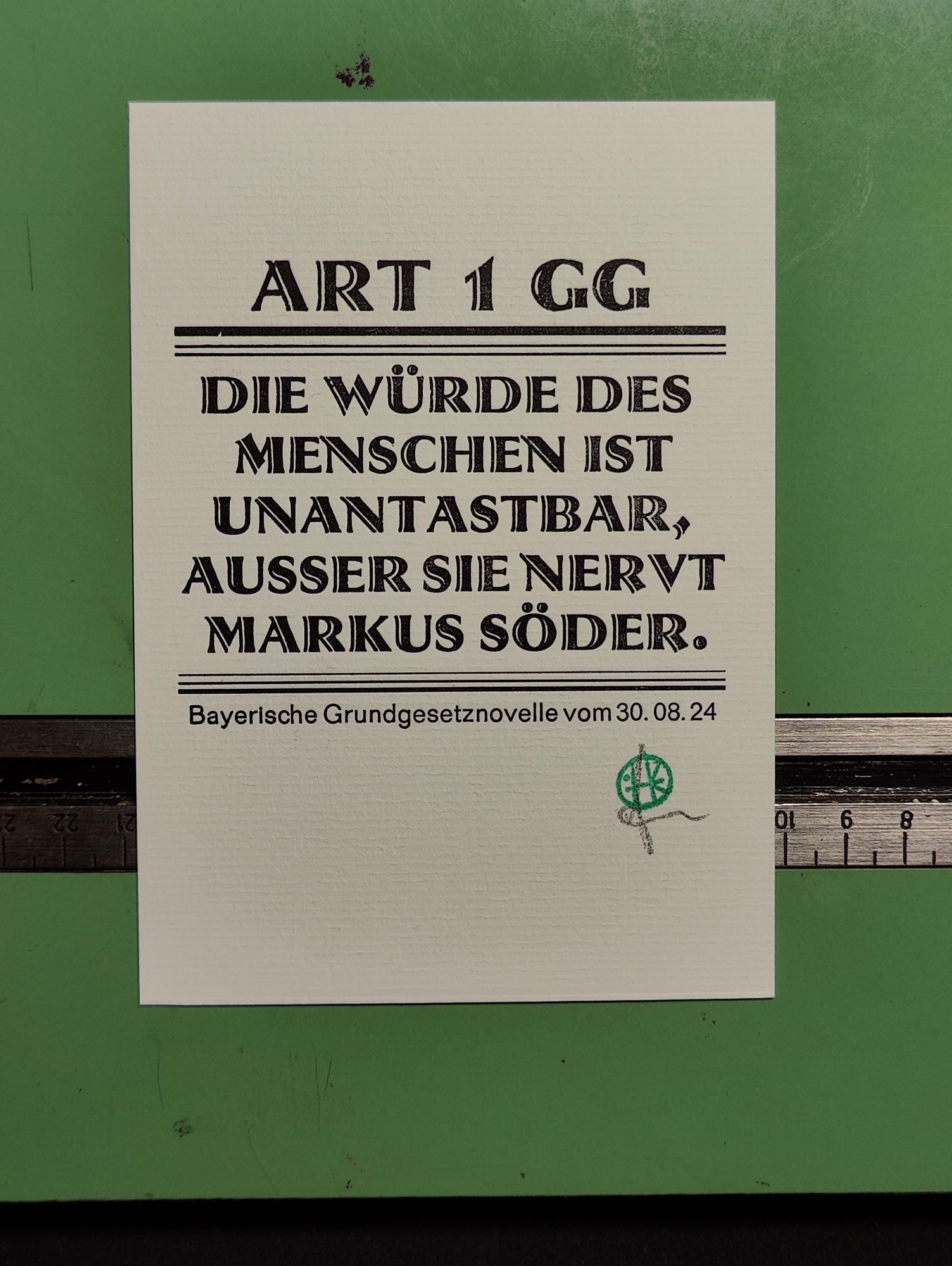 Foto einer Karte in Bleisatz in der Schrift Atrax von 1926. Auf ihr steht: 

Art 1 GG
Die Würde des Menschen ist unantastbar, ausser sie nervt Markus Söder. 

Klein darunter steht in Folio Bayerische Grundgesetznovelle vom 30. 08. 24