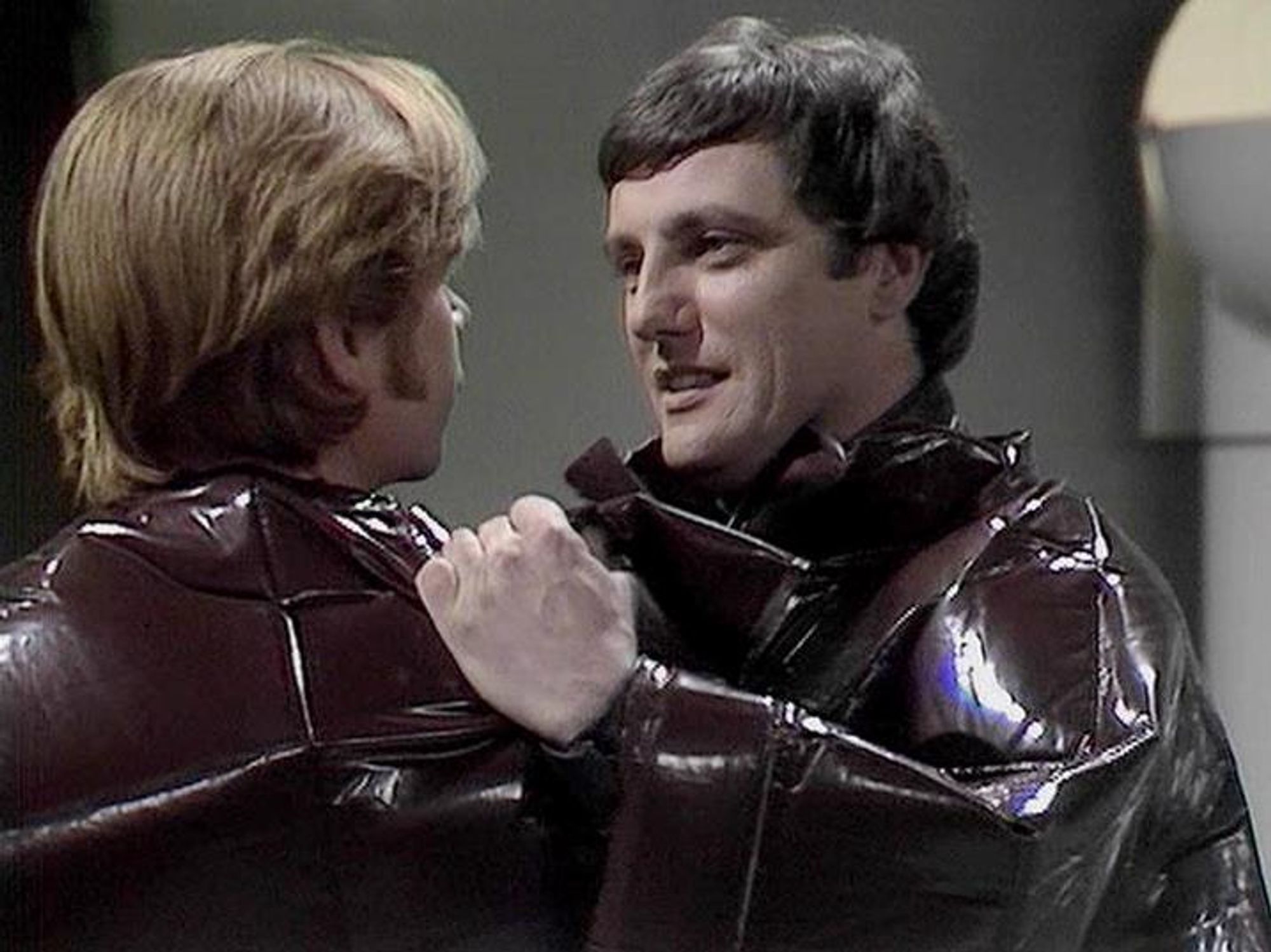 

ChatGPT4 describes the image as: "The image shows two men dressed in shiny, dark-colored outfits. They are engaged in a close, face-to-face interaction, possibly a confrontation or an intense conversation, as they are each gripping the other's clothing. The setting appears to be indoors, with a simple and somewhat futuristic background typical of science fiction sets. 

Since I cannot identify individuals in images, I cannot tell you if Paul Darrow is in this image."

Blakes7Bot, version 3.7.28. Upload retries: 0. bluesky.py version: 3.12