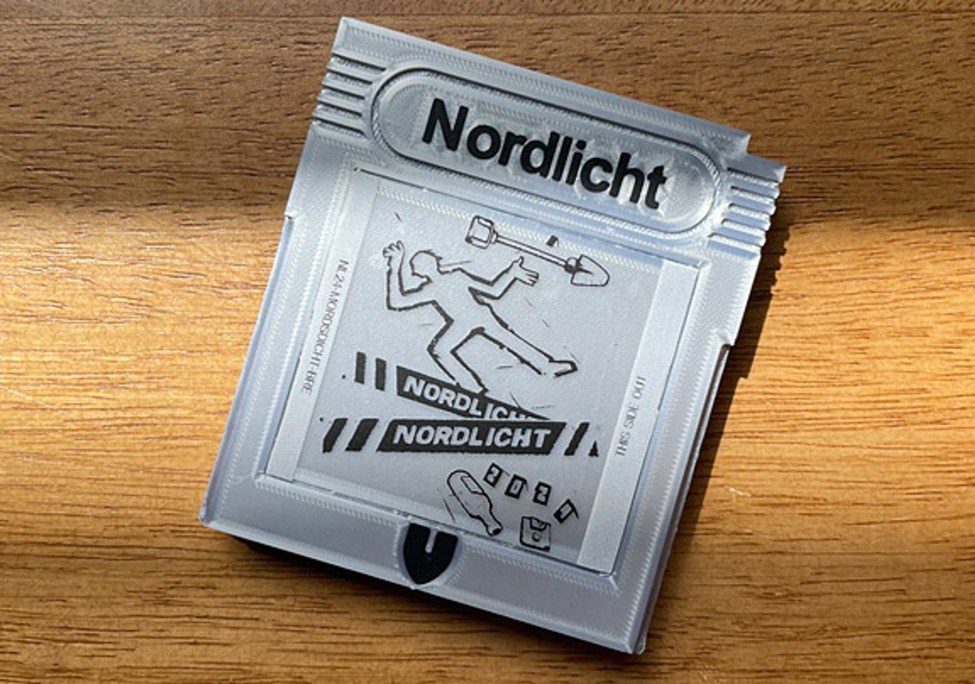 A 3D-printed Game Boy cartridge labelled "Nordlicht" with a stylized crime scene