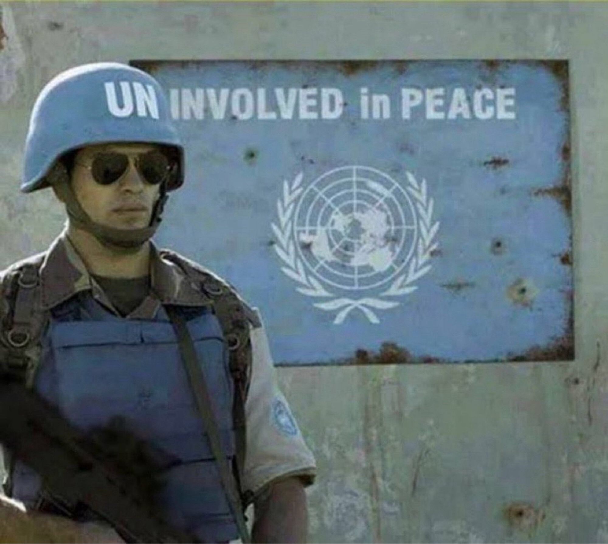 UN-Blauhelmsoldat steht so unglücklich vor einem rostigen UN-Schild, dass die Lettern auf seinem Helm und auf dem Schild den Schriftzug "UNINVOLVED IN PEACE" ergeben