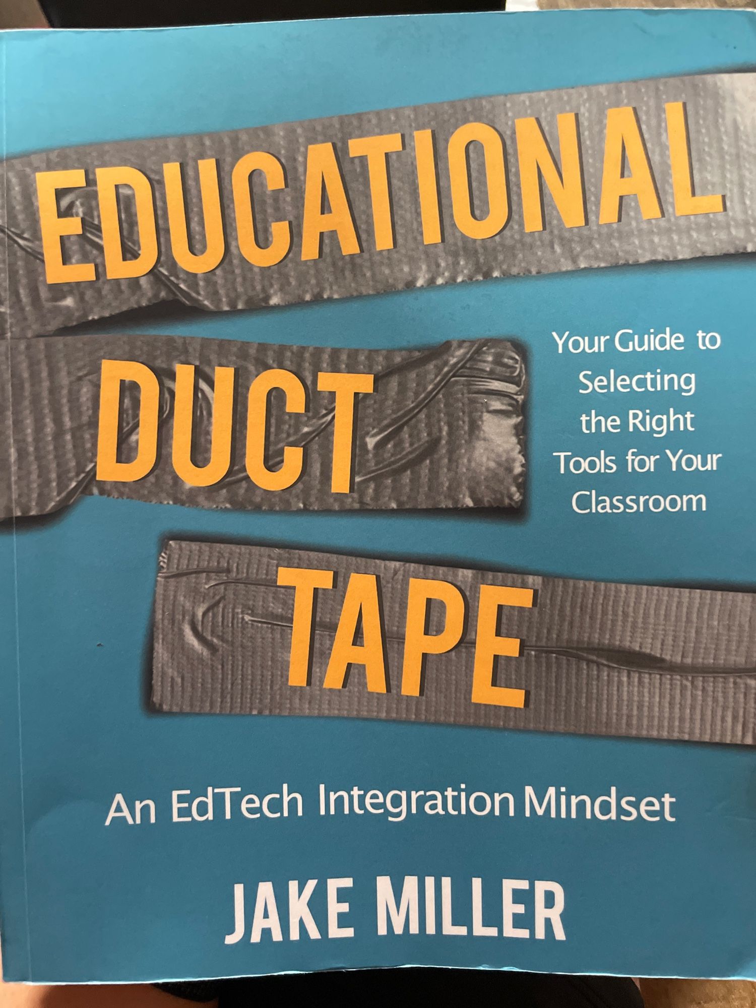 Picture of the book titled Educational Duct Tape by Jake Miller. Blue cover with duct tape across it with the title written on it. 