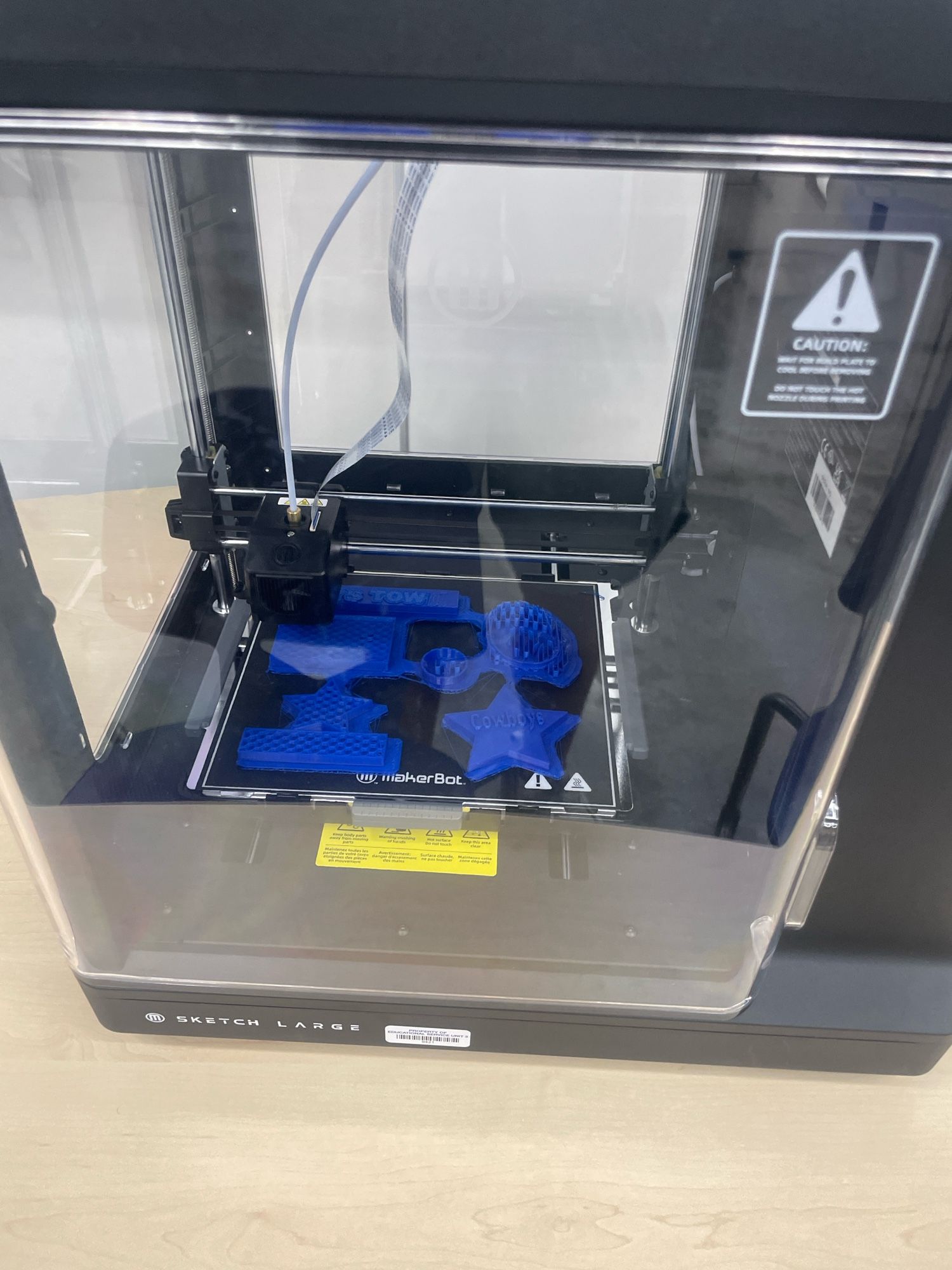 3D printer with objects being printed in blue filament.