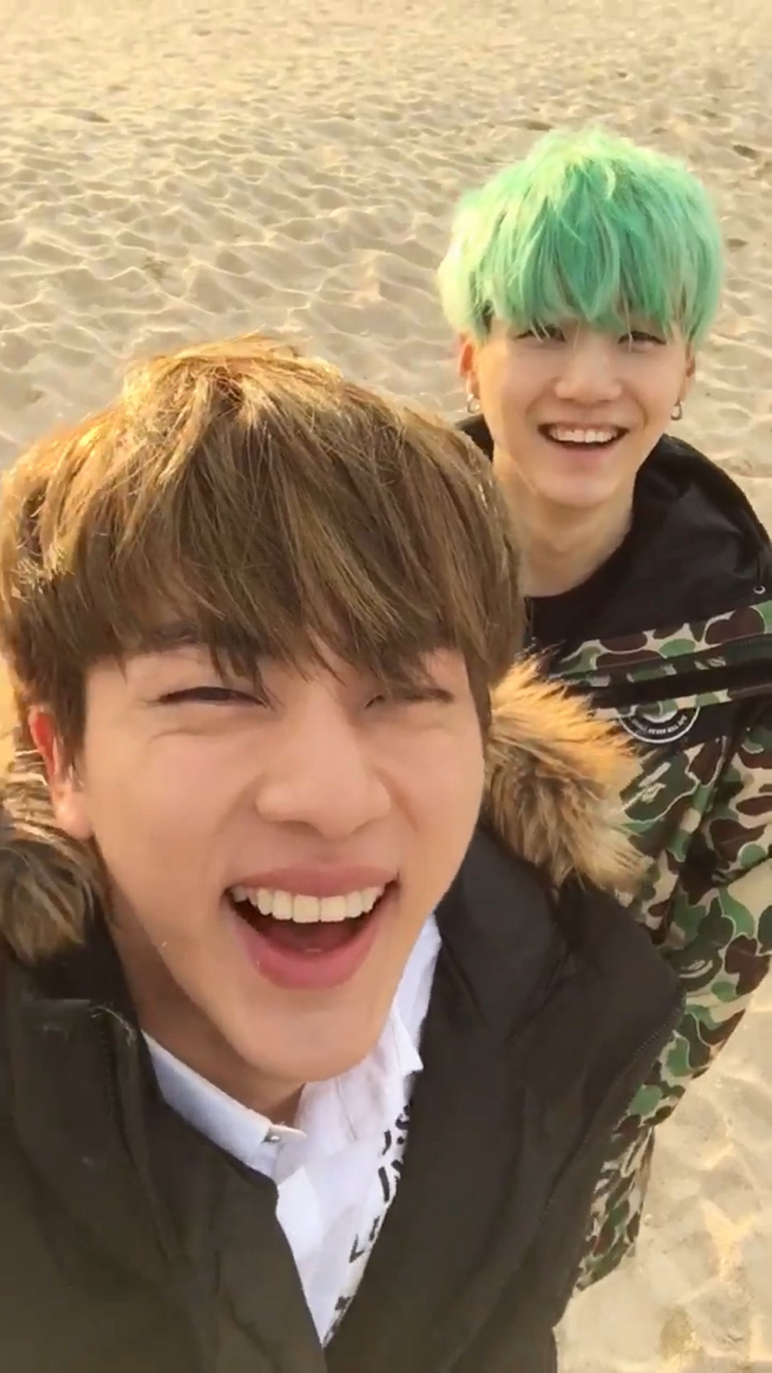 Kim Seokjin and Min Yoongi from BTS smiling at the beach.