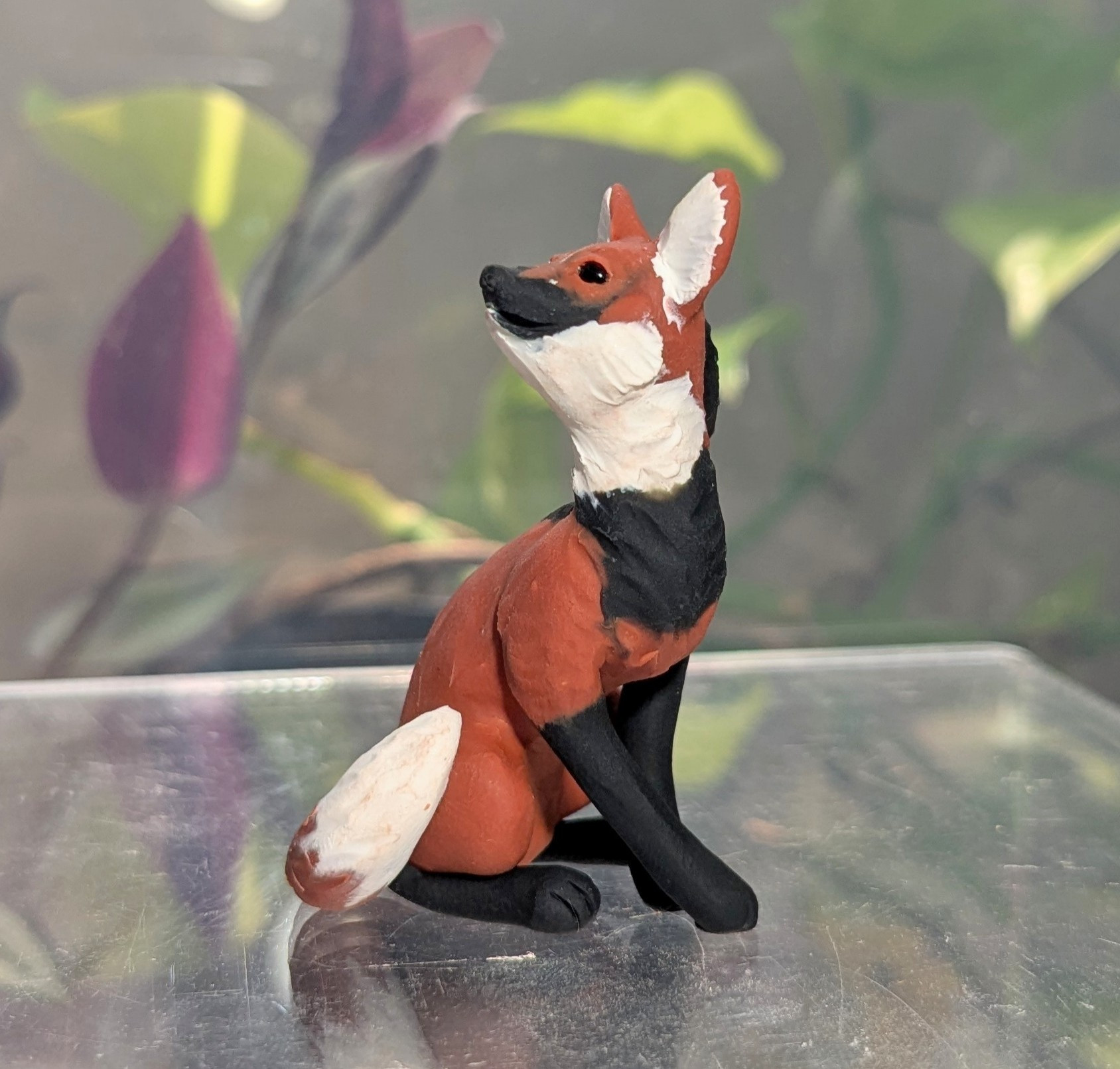 A figurine of a Maned Wolf. She is seated, tail curled over hip, looking warily over her shoulder.