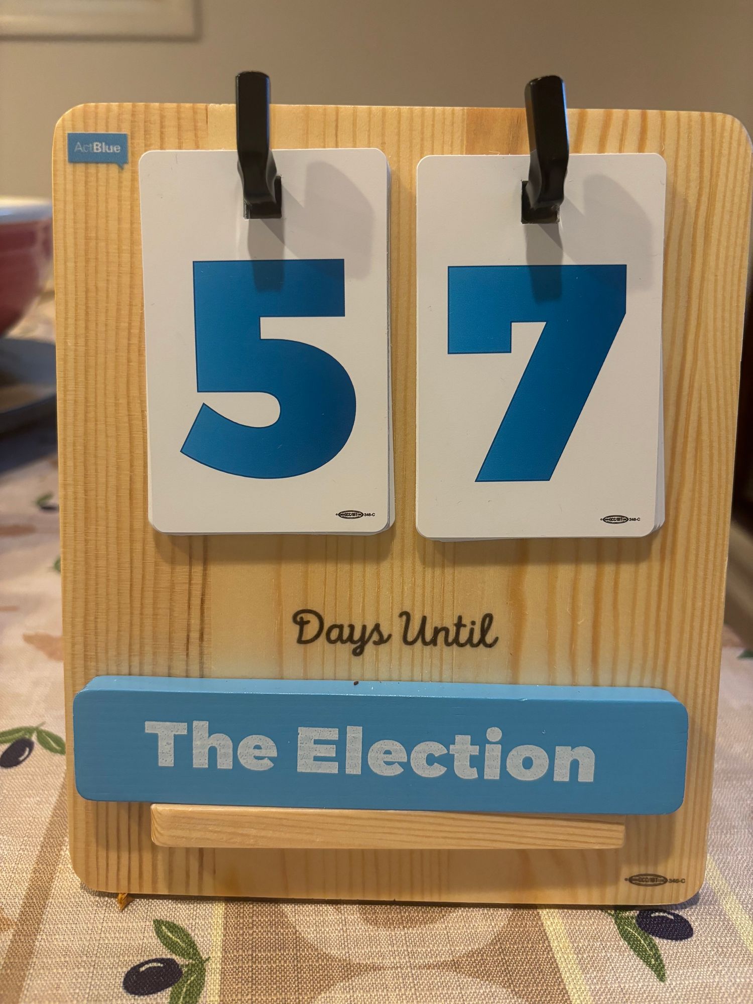 A countdown calendar indicating 57 days left until the election, displayed on a wooden stand with blue and white cards.