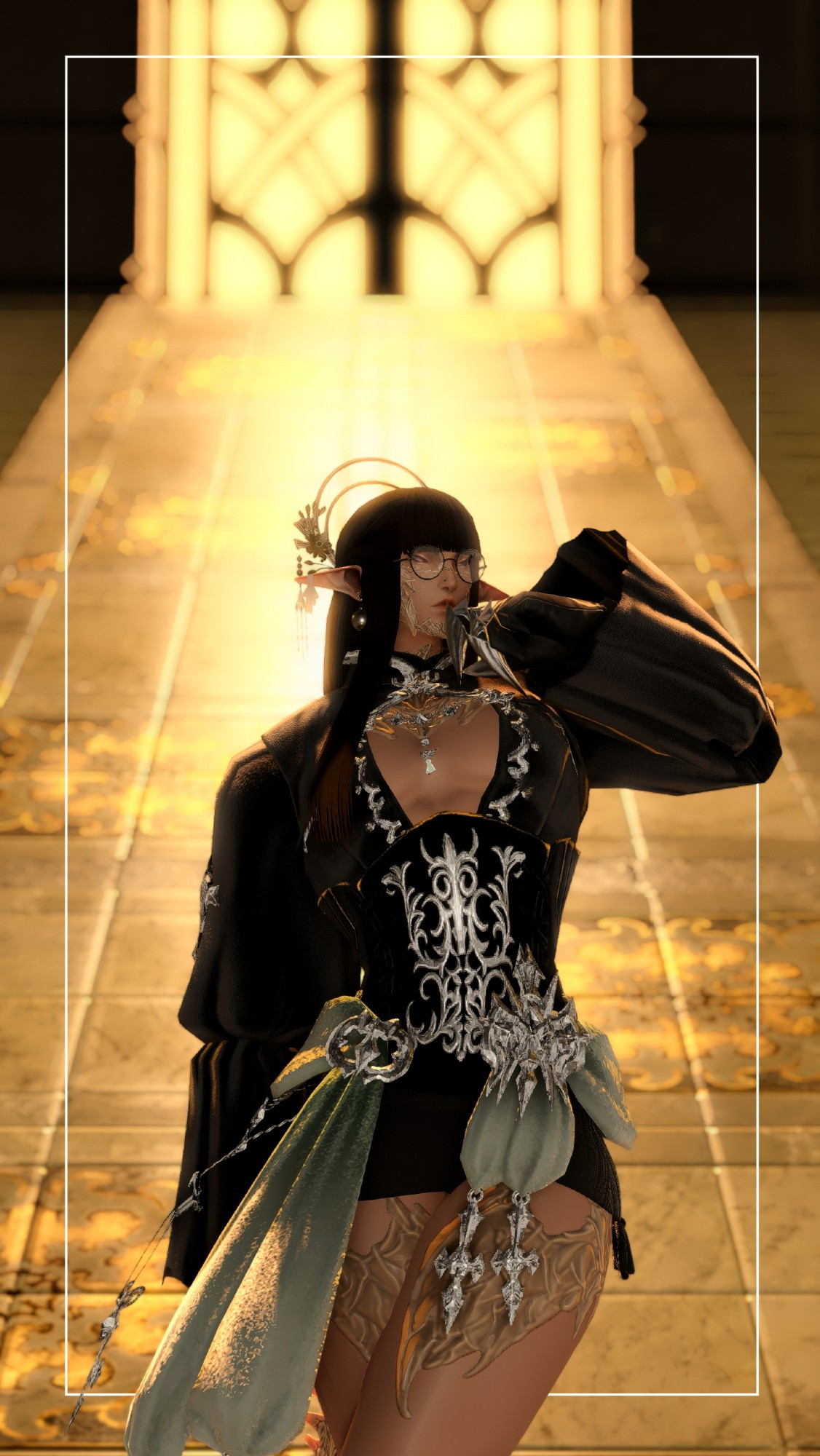 A male Raen Au Ra wearing a gothic top with a black and silver corset, silver accents up to the collar. He wears a silver headpiece with flowers and two hoops, one bigger than the other. He has elf ears with globe earrings, one earring with a bandage at the tip of the ear. Faint purple eyes with golden hues in them, halfway closed. He also wears black rimmed circular glasses. Long, straight hair with blunt bangs. Gloves with two silver claws at the index and middle finger. Also wears a short knitted black skirt underneath. Tied to the top is a light, pastel green sash with silver accents. The background is of a golden tinted window with a black window frame, marble flooring with golden hues leading up to the window.