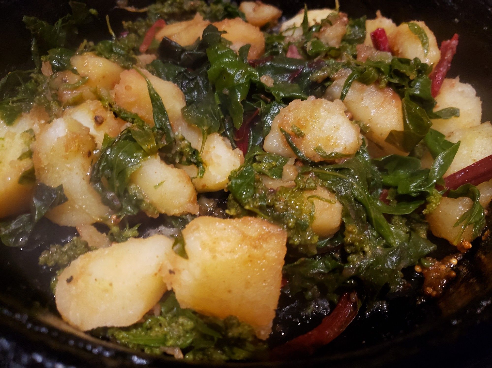 Pan full of home cooked potatoes and greens, feying nicely