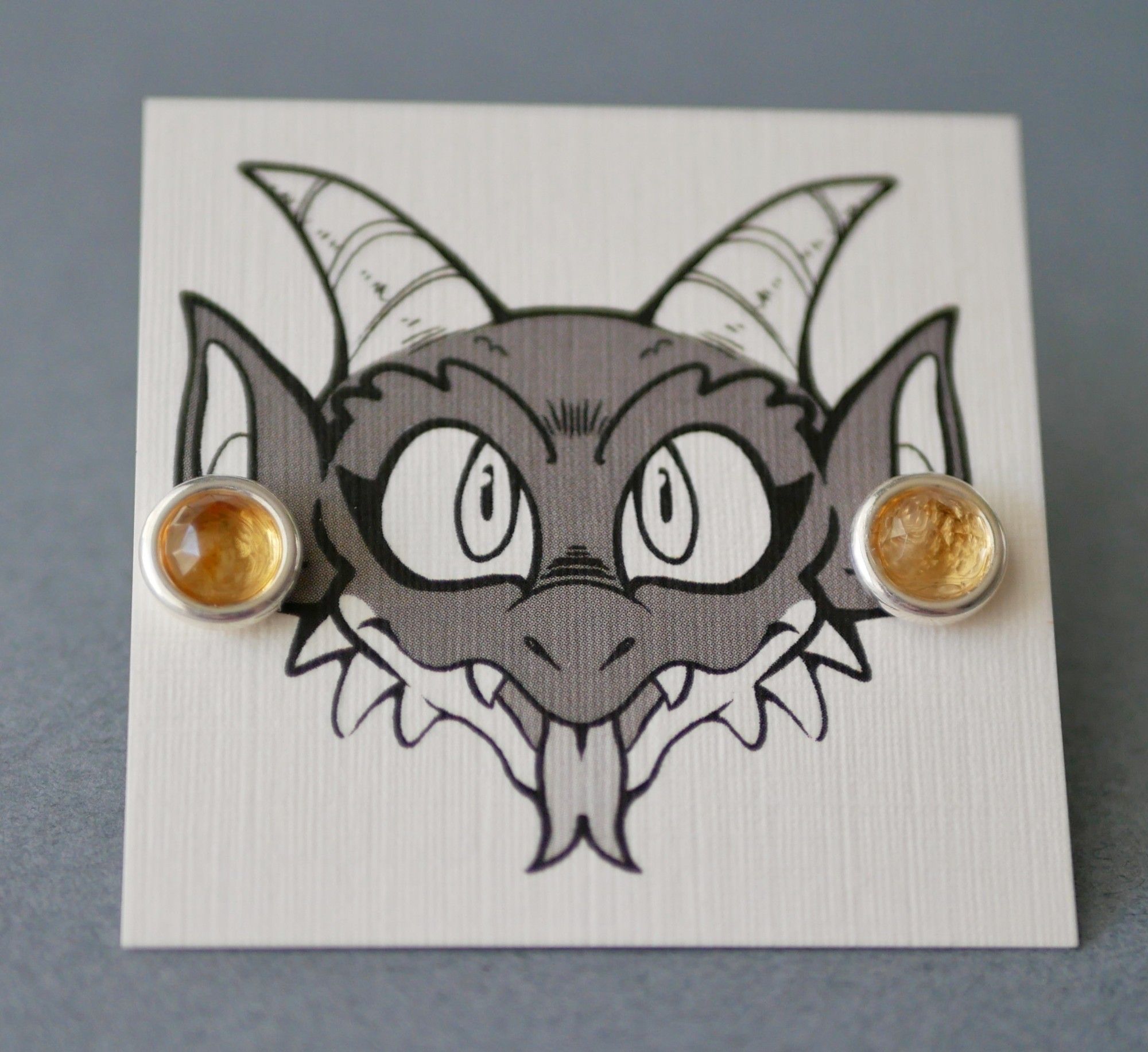 rose cut citrine earrings on an earring card with Bauble the kobold on it looking like he's wearing the earrings