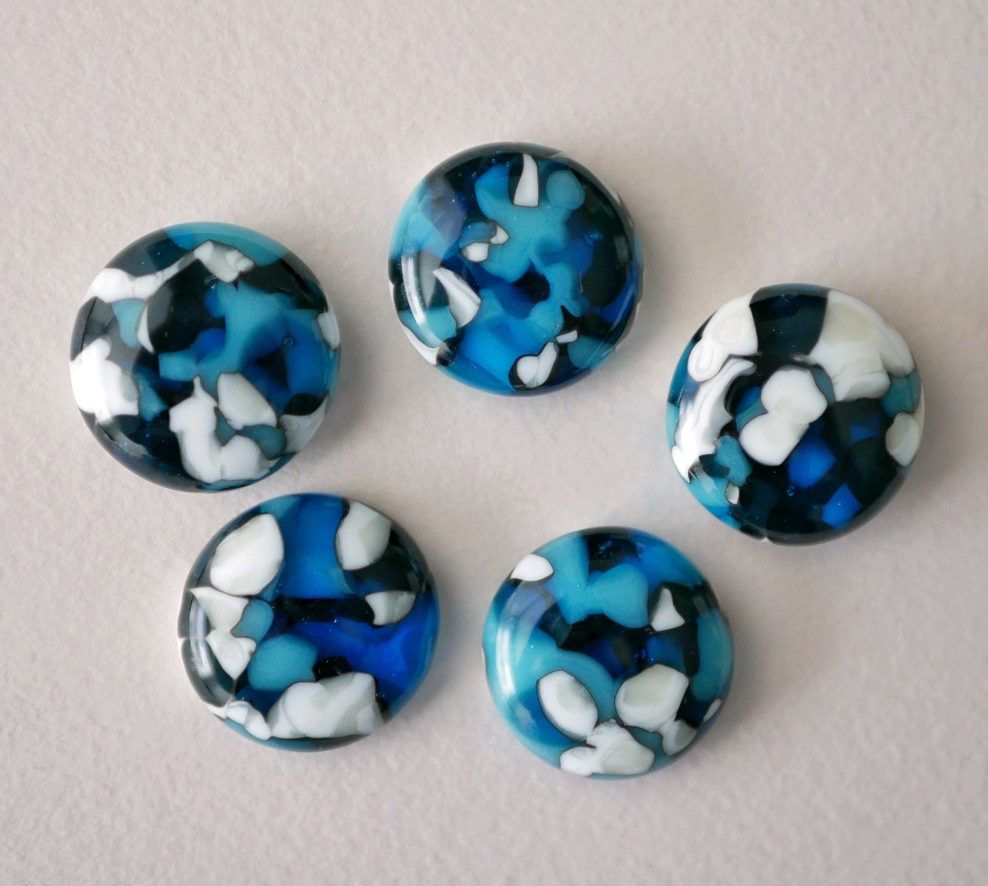 a group of blue and white cabochons where the edges between blue and white are very dark