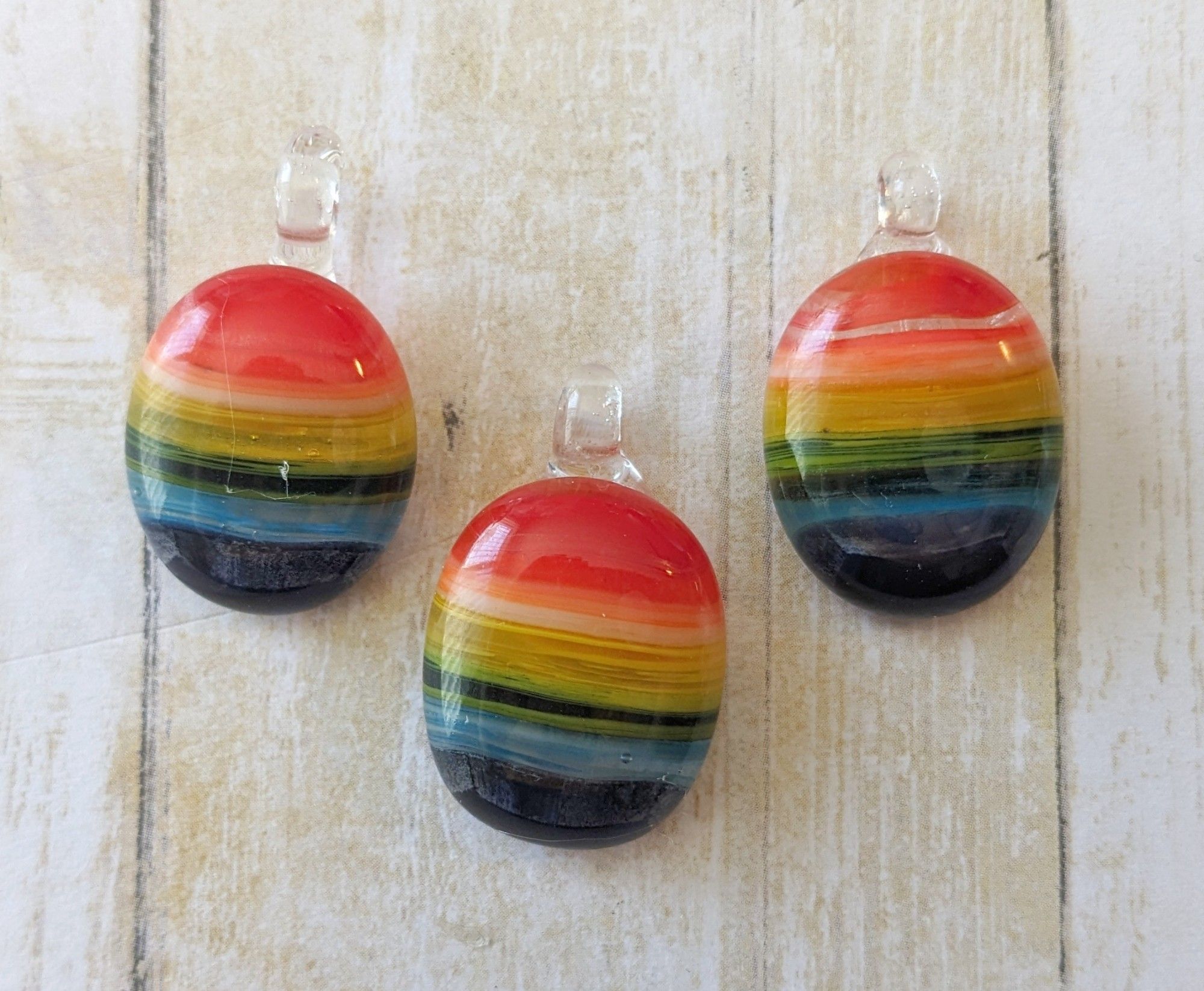 three rainbow pendants with clear bails