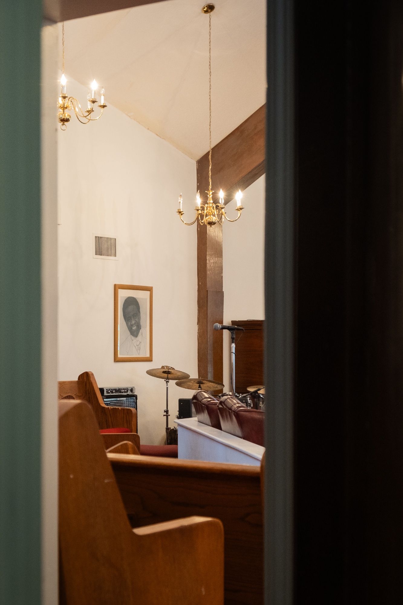 A view through a door to the bandstand. A black and white portrait of Al Green hangs above the drums.