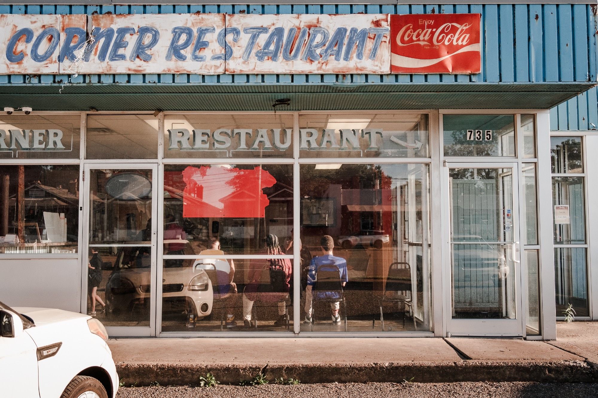 Customers wait for their orders inside the storefront of a barbecue joint.