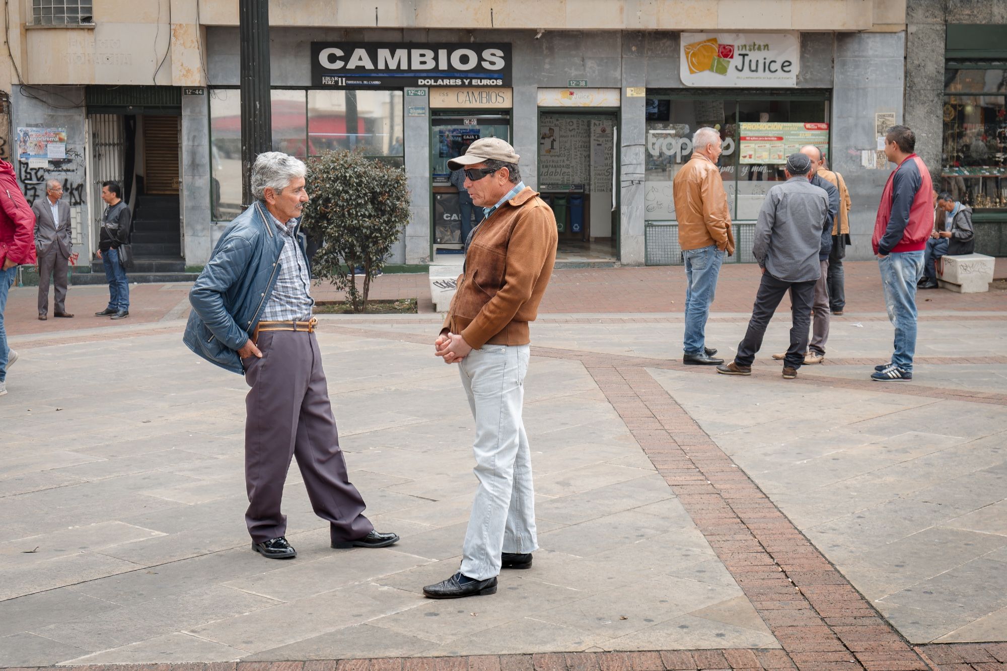 Emerald salesmen loosely congregate in an open plaza.