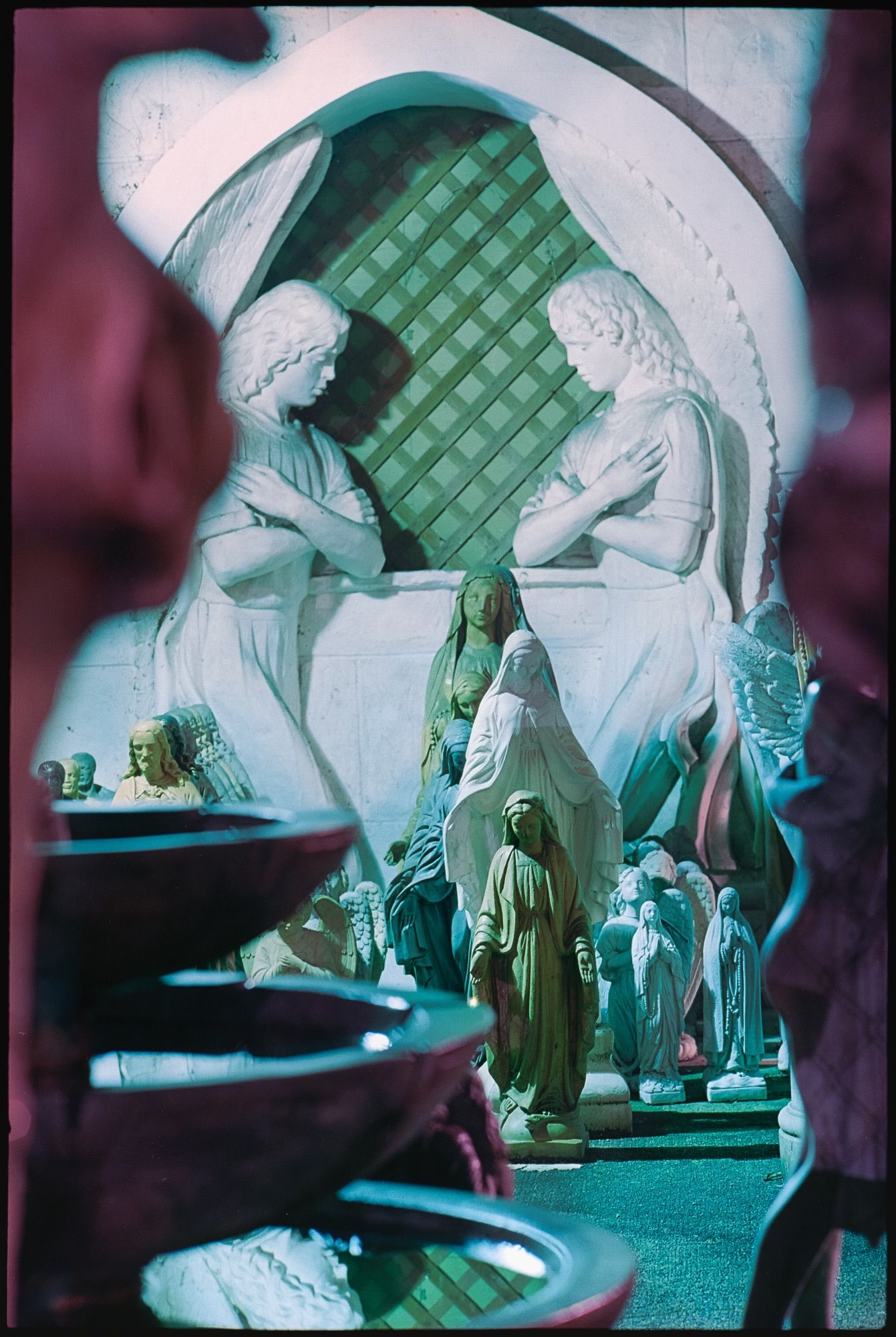 Two statues of women with their arms folded mirror each other amongst assorted smaller statues of religious figures.