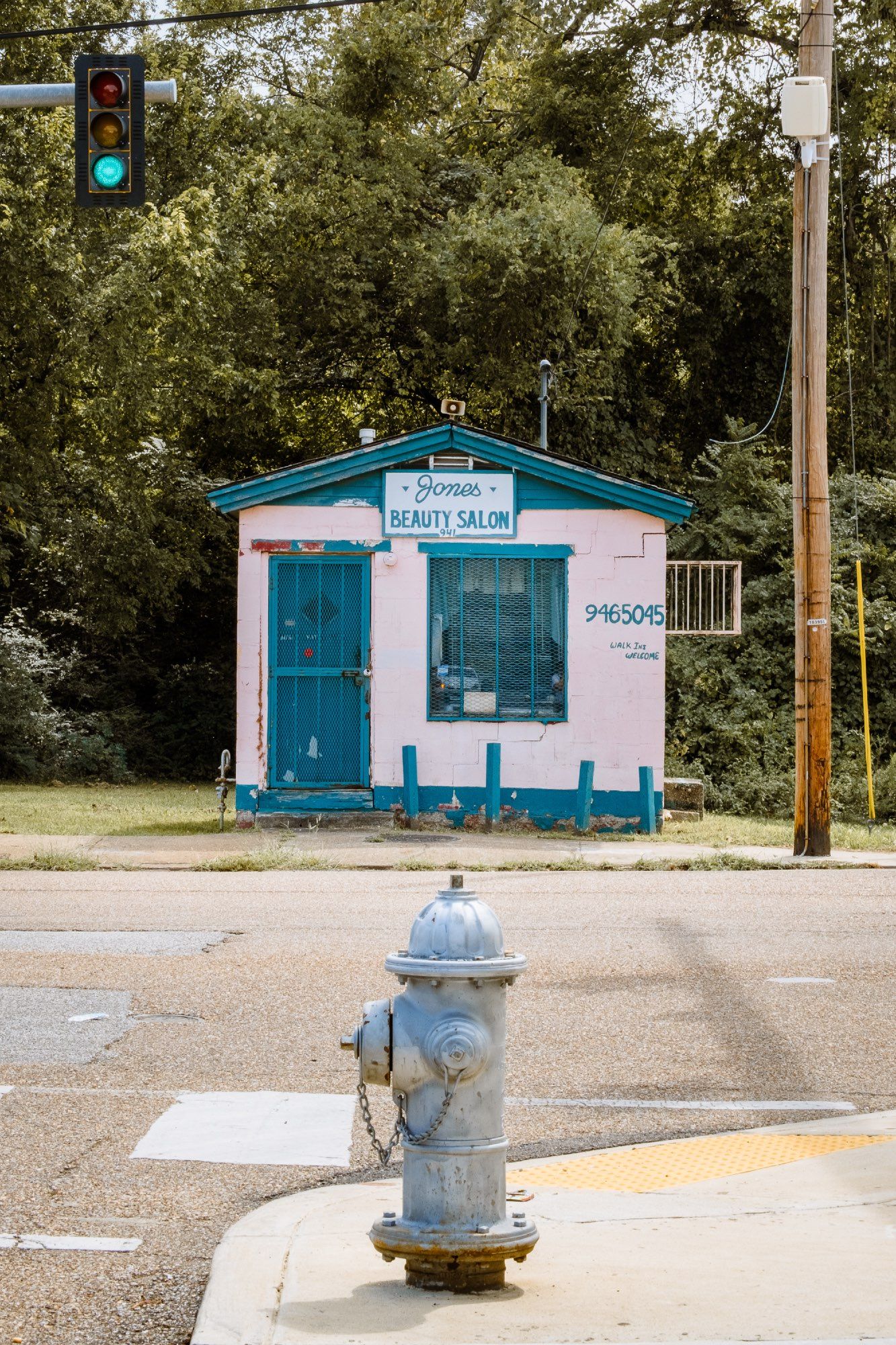 The pink and teal form of Jones Beauty Salon, the smallest commercial building in Memphis, sits at the end of a street.