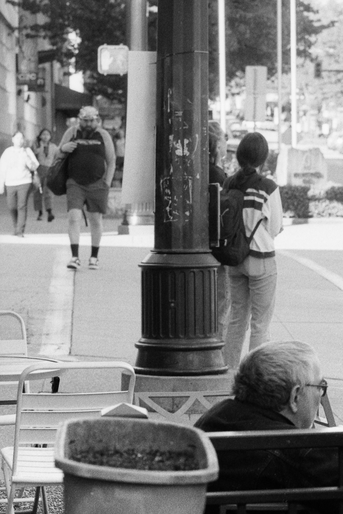 A seated man daydreams while gazing at a busy intersection.