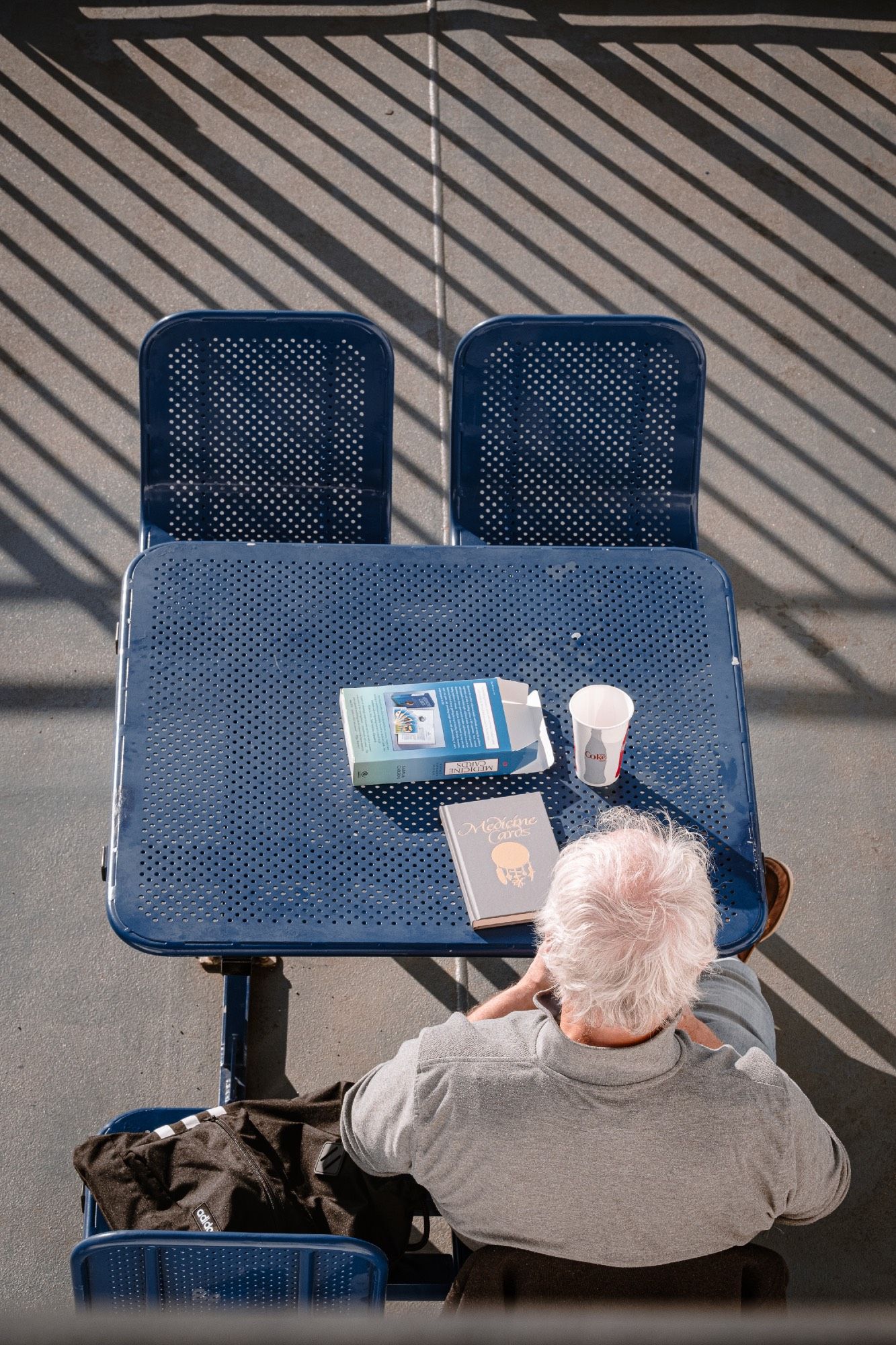 A man spends time reading at a small table on deck.