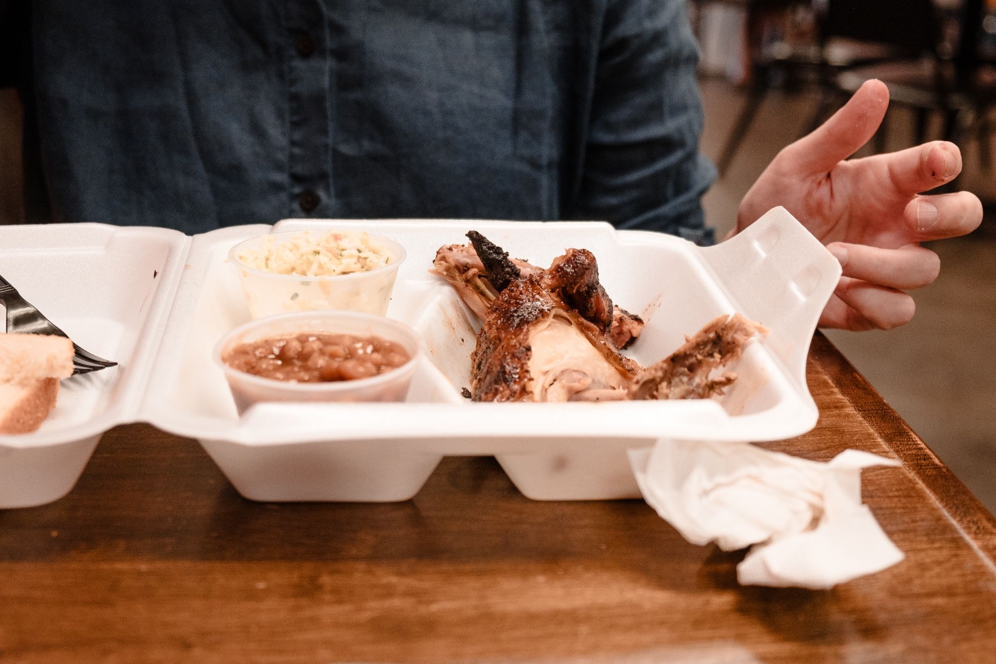 A woman gets ready to tuck into her Cornish hen and two sides.