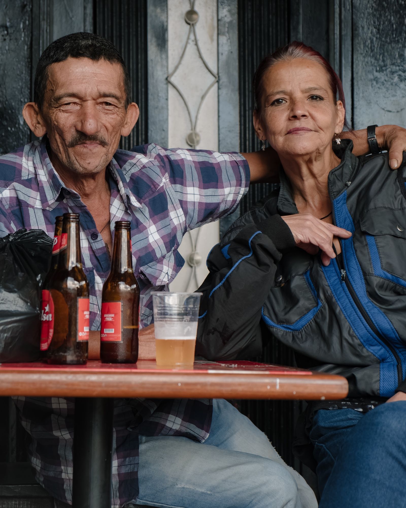 A couple at a bar pose behind beer bottles for what was supposed intended to be a candid photo.