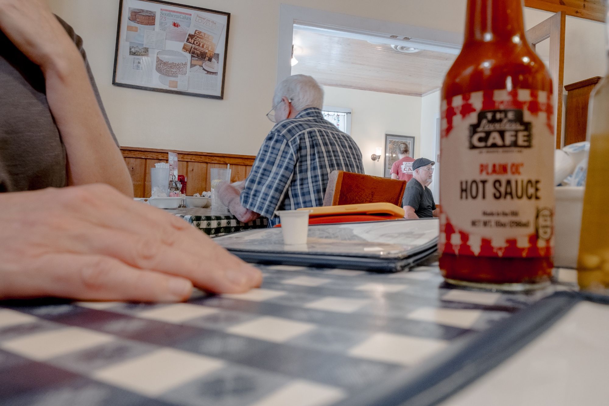 Various restaurant patrons as viewed through the clutter of a breakfast table.