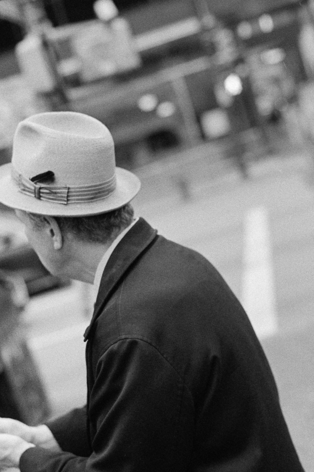 A man in a hat mindlessly rubs his hands while glancing into the distance.