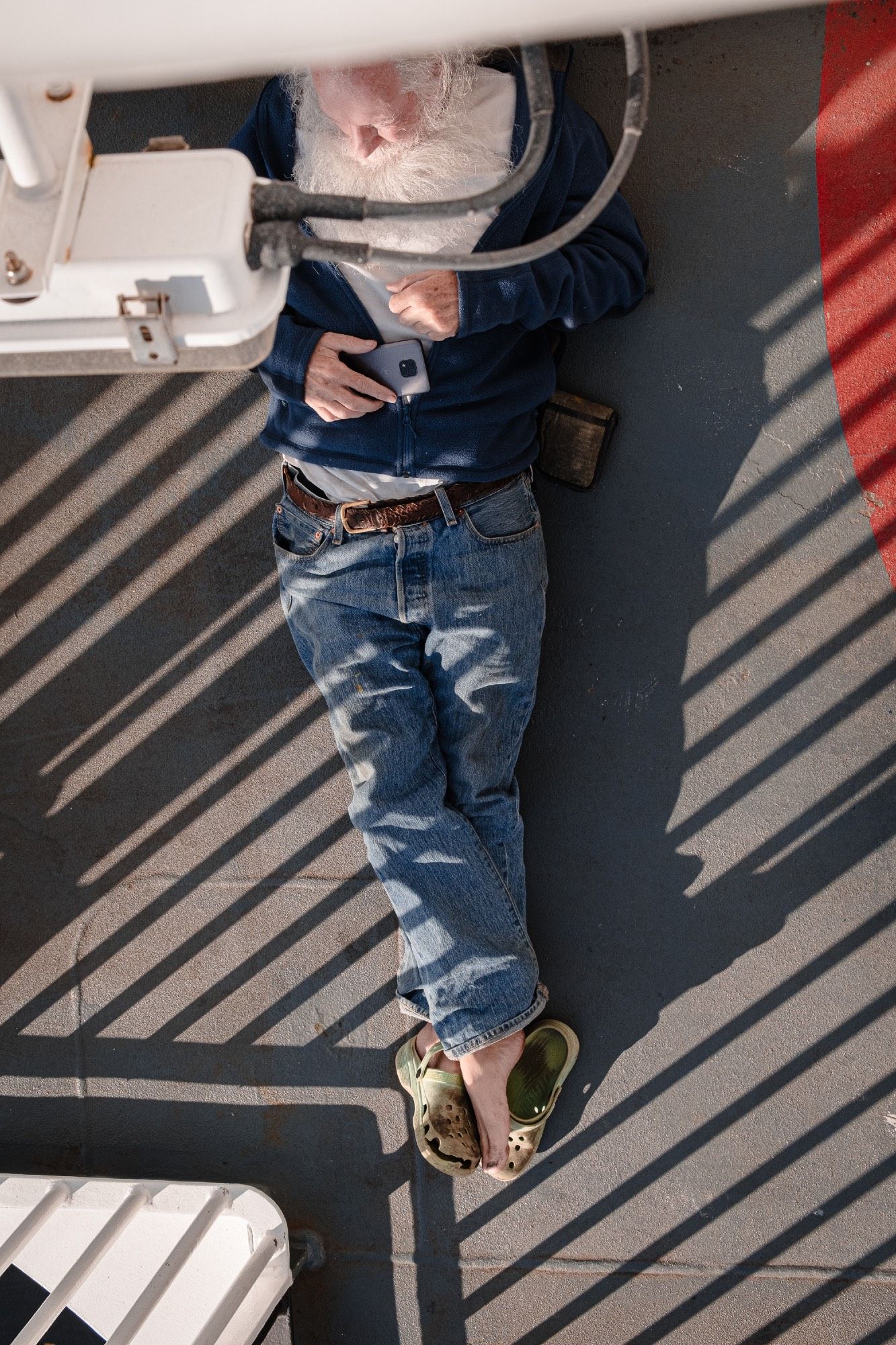 A man with a beard reclines lazily on the ship’s deck.