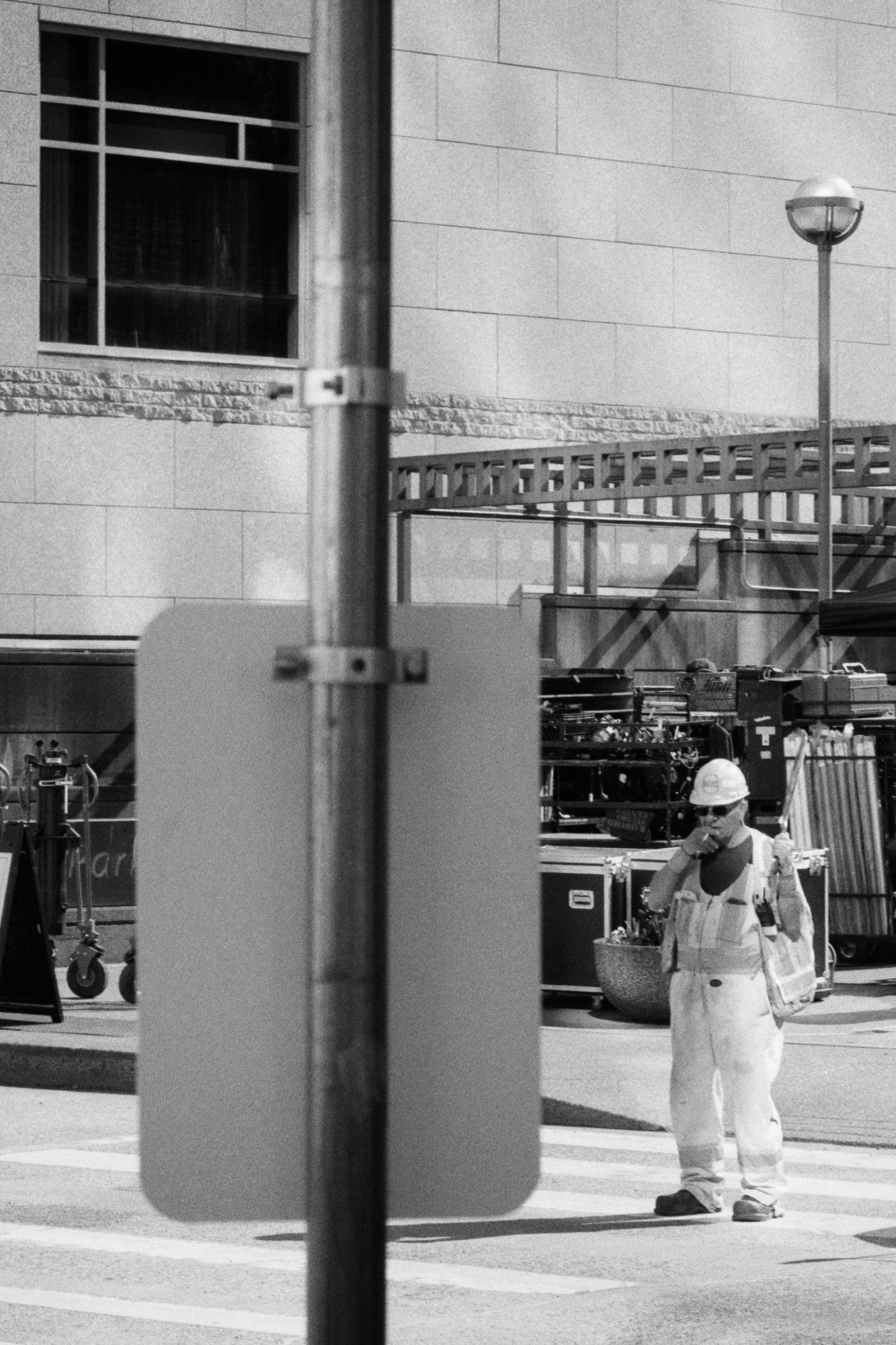 A man guides traffic around a movie shoot as he enjoys a cigarette.