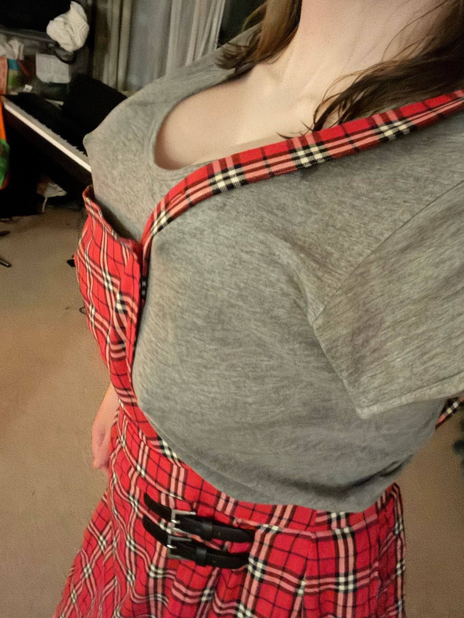 A girl showing out four breasts under the gray shirt and wearing a plaid skirt.