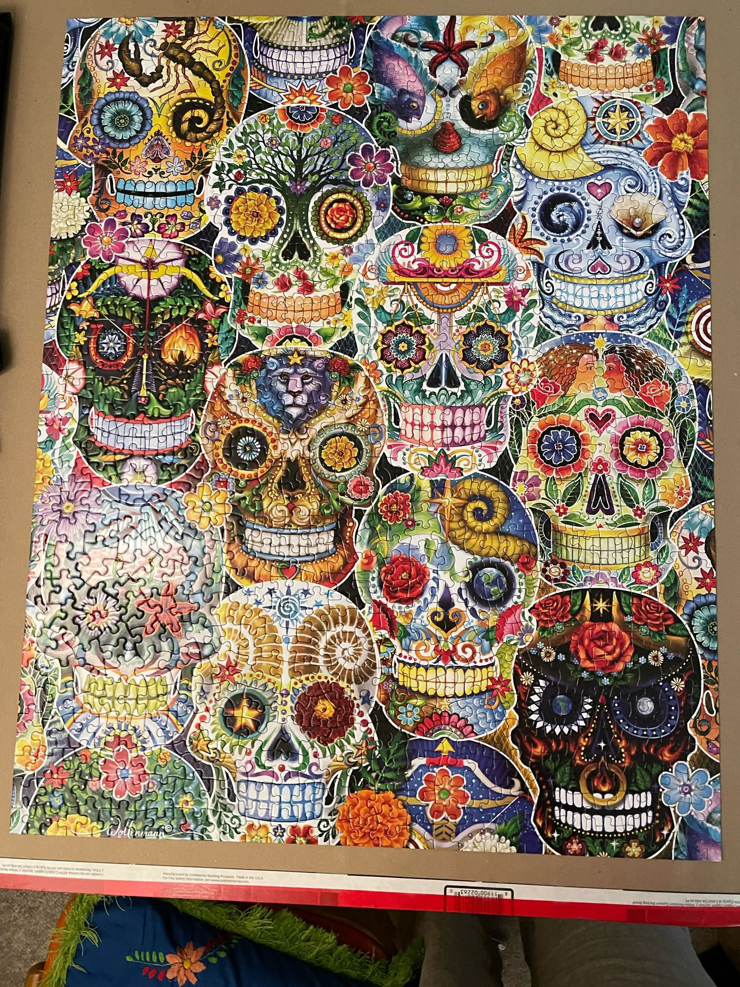 Jigsaw puzzle featuring 12 multicolored calaveras or skulls made out of repeating patterns like flowers, spirals, stars, bows and arrows, and sea life. 