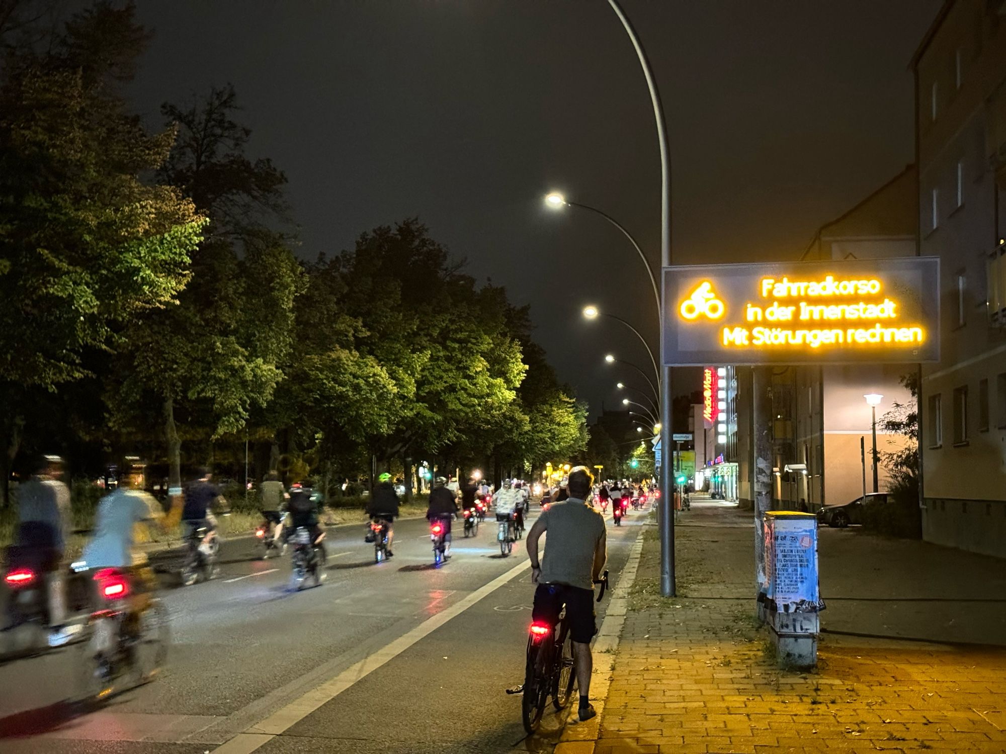 Großes LED Display  mit „fahrradkorso in der Innenstadt“ Nebendran sieht man die CM, nachts