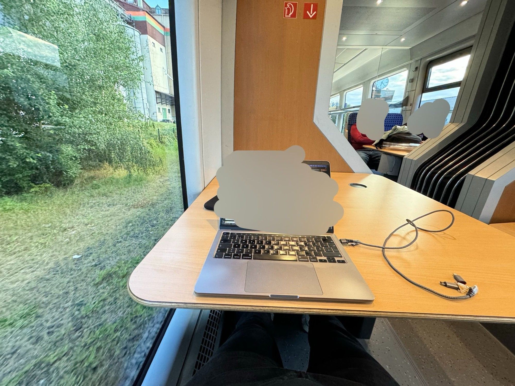 Innerhalb eines Regional Zuges. An einem Tisch, der groß und an dem man bequem sitzen kann. mit großem Fenster auf der linken seite. Laptop auf dem Tisch