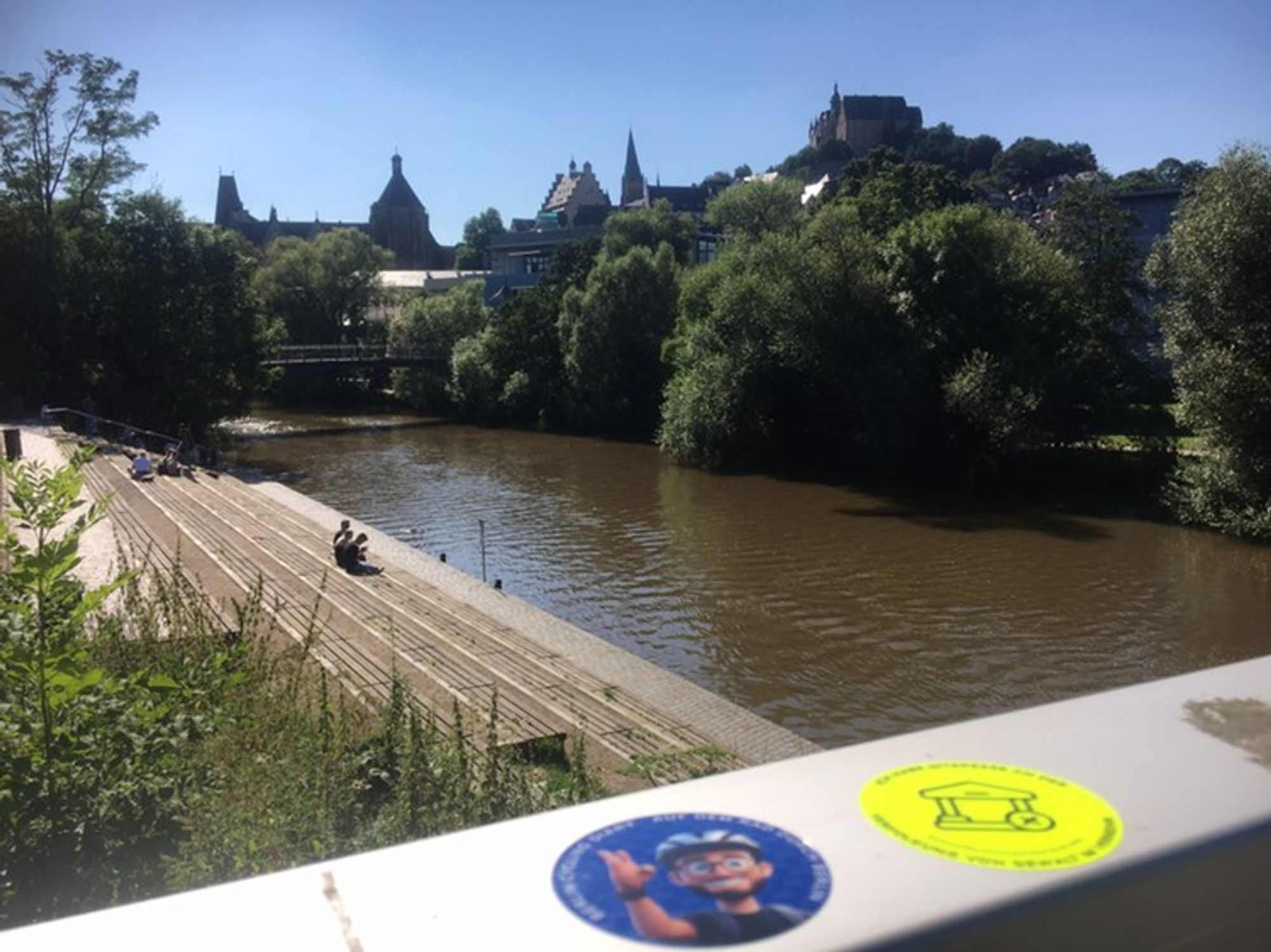 Geländer auf das ein Berlin Cycling Diary Sticker geklebt ist, im Hintergrund das Marburger Schloss