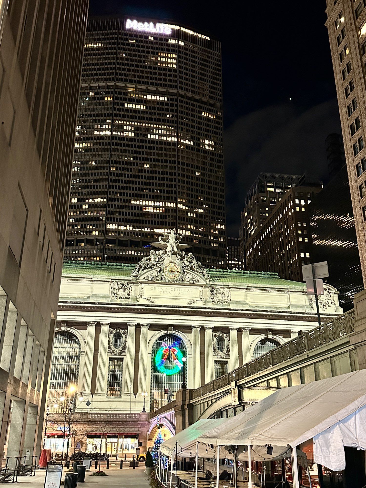 Grand central station New York City with the MetLife skyscraper behind and a holiday light up wreath on the front of grand central