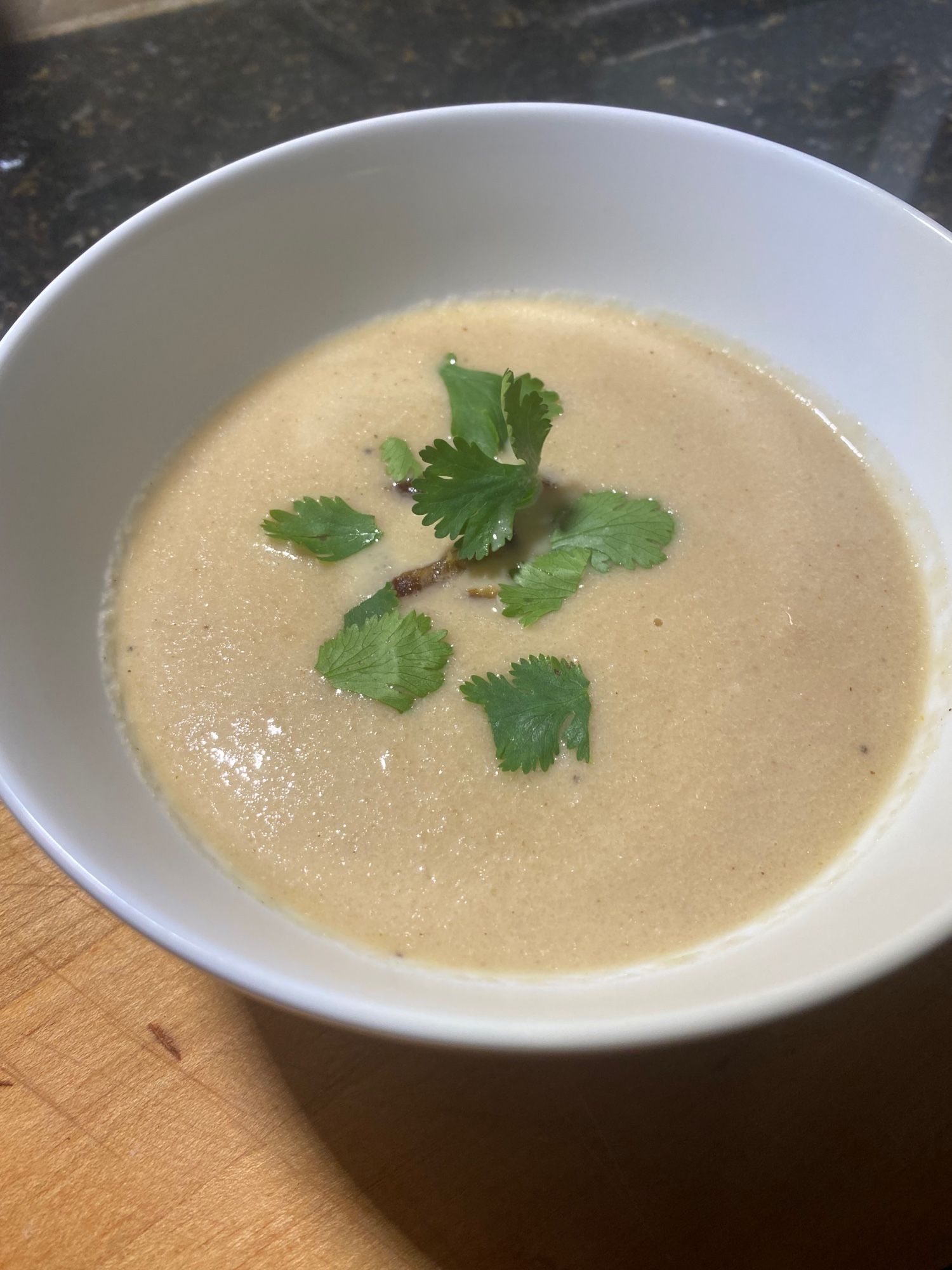 A white bowl on a cutting board and granite counter holds a creamy, pale tan soup topped with small slices of Medjool date and green cilantro leaves.

I roasted a head of cauliflower florets tossed with EVOO, cayenne, salt and pepper for about 20 minutes. Meantime, I sautéed a red onion and 3 crushed garlic cloves in about 2 T of butter. The roasted cauliflower got added to the onion and garlic, along with a sprinkle of ras el hanout. I added Better Than Bouillon vegetable broth to leftover chicken broth to make 4 cups and poured into the pot. Simmered about 20 minutes, added about 2 tsp sherry vinegar, then pureed using a stick blender. Added leftover heavy cream (about 1/4 cup) to the smooth soup.