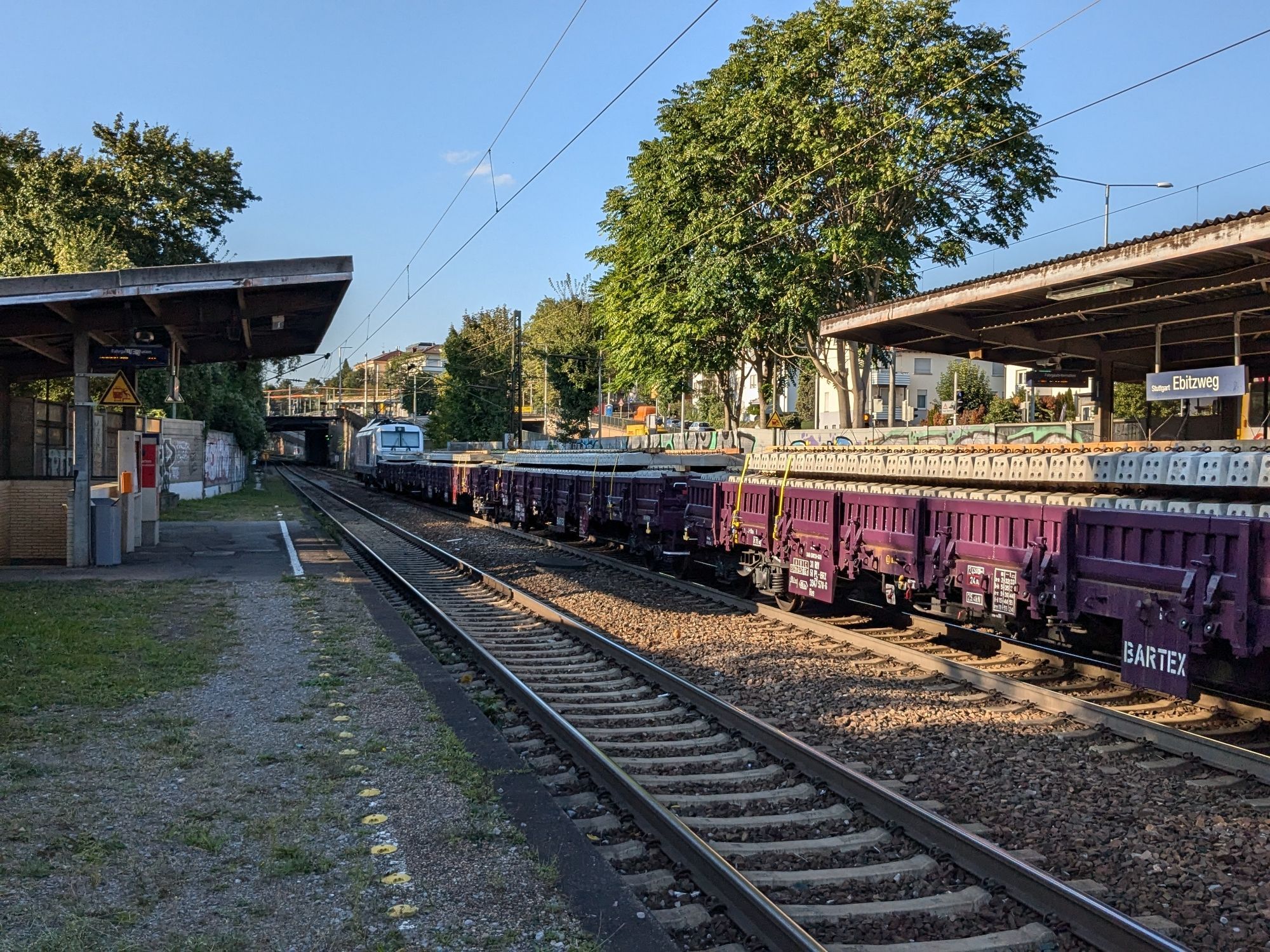 A Vectron electric locomotive pulling a freight train with railway sleepers on them