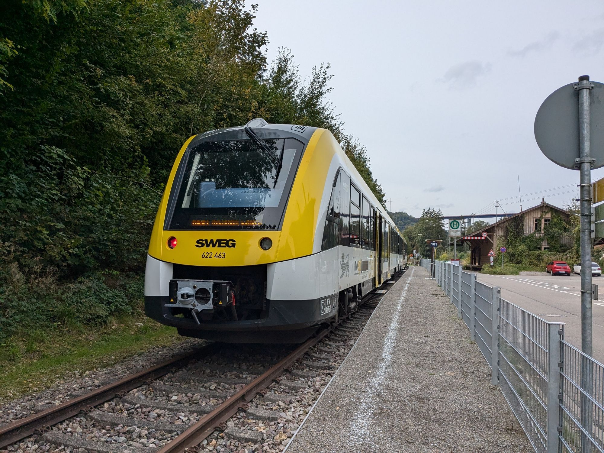 Triebwagen 622 463 der SWEG steht auf Gleis 101 im Bahnhof Eyach HzL. Der Bahnsteig besteht aus aufgeschüttetem Kies mit einem aufgemalten Strich. Rechts ein Zaun und dahinter eine Straße. Auf der gegenüberliegenden Seite befindet sich (nicht sichtbar) der DB-Bahnhof Eyach