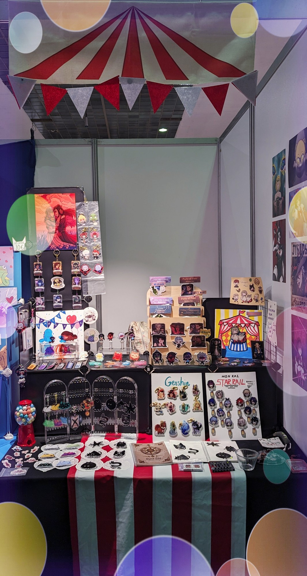 A picture of a circus themed booth with a variation of merchandises like charms, prints and stickers. 