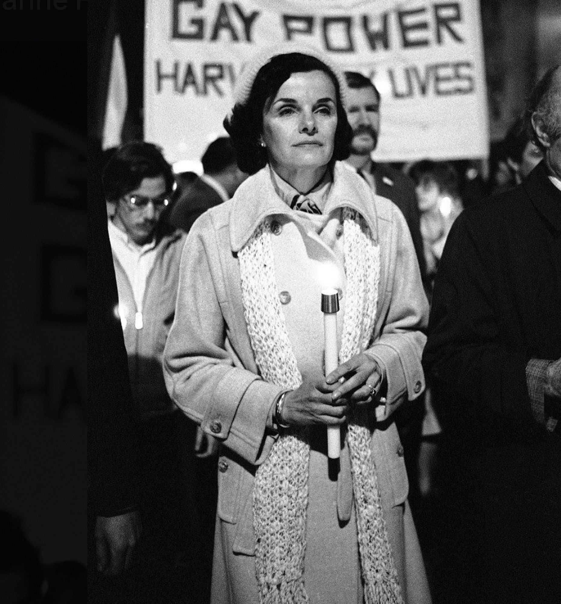 Photo of Dianne Feinstein in the 1970s or early 1980s marching in a parade in front of a Gay Power/Harvey Milk Lives placard.