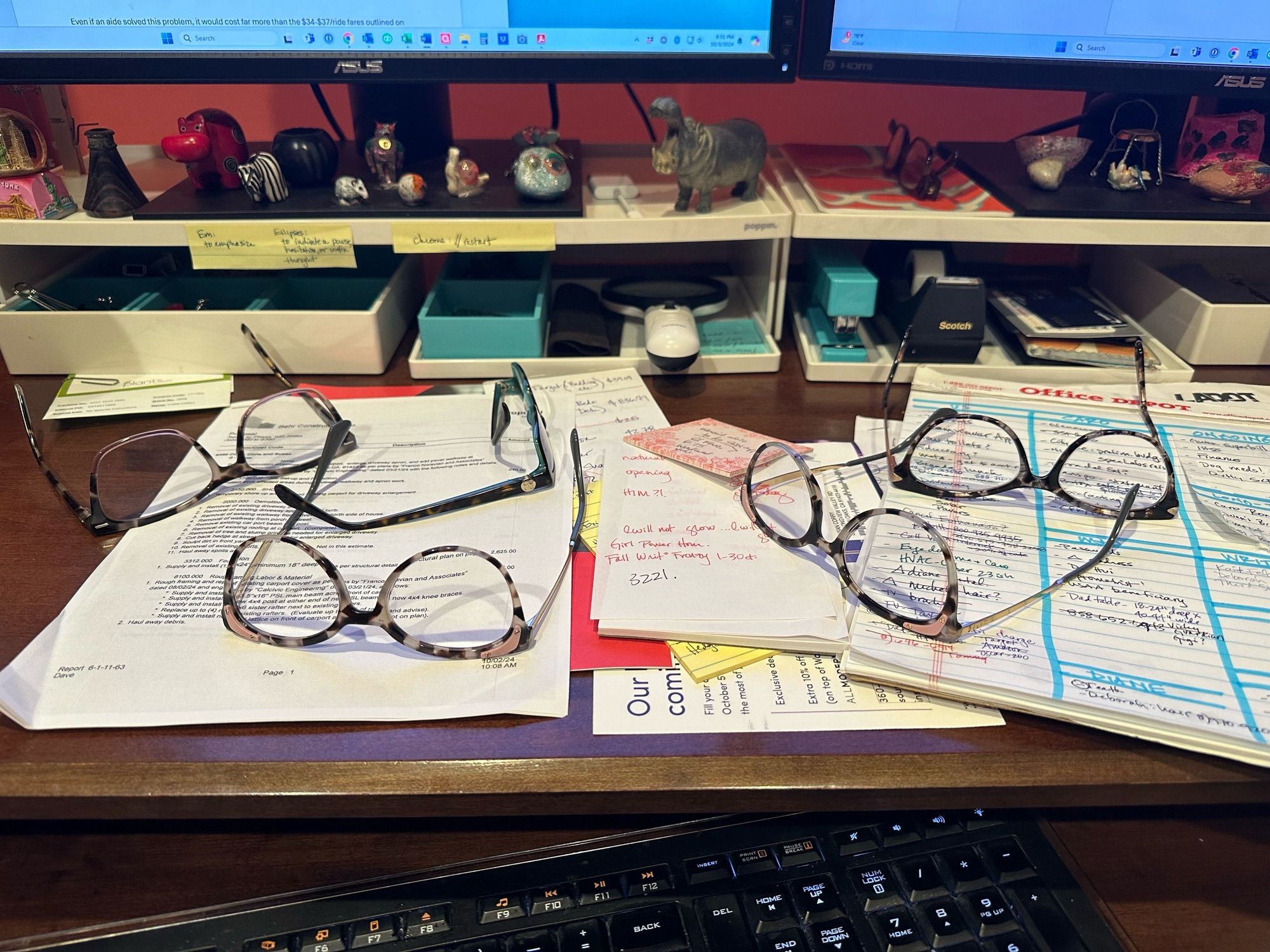 Photo of messy desk and FIVE pairs of glasses.