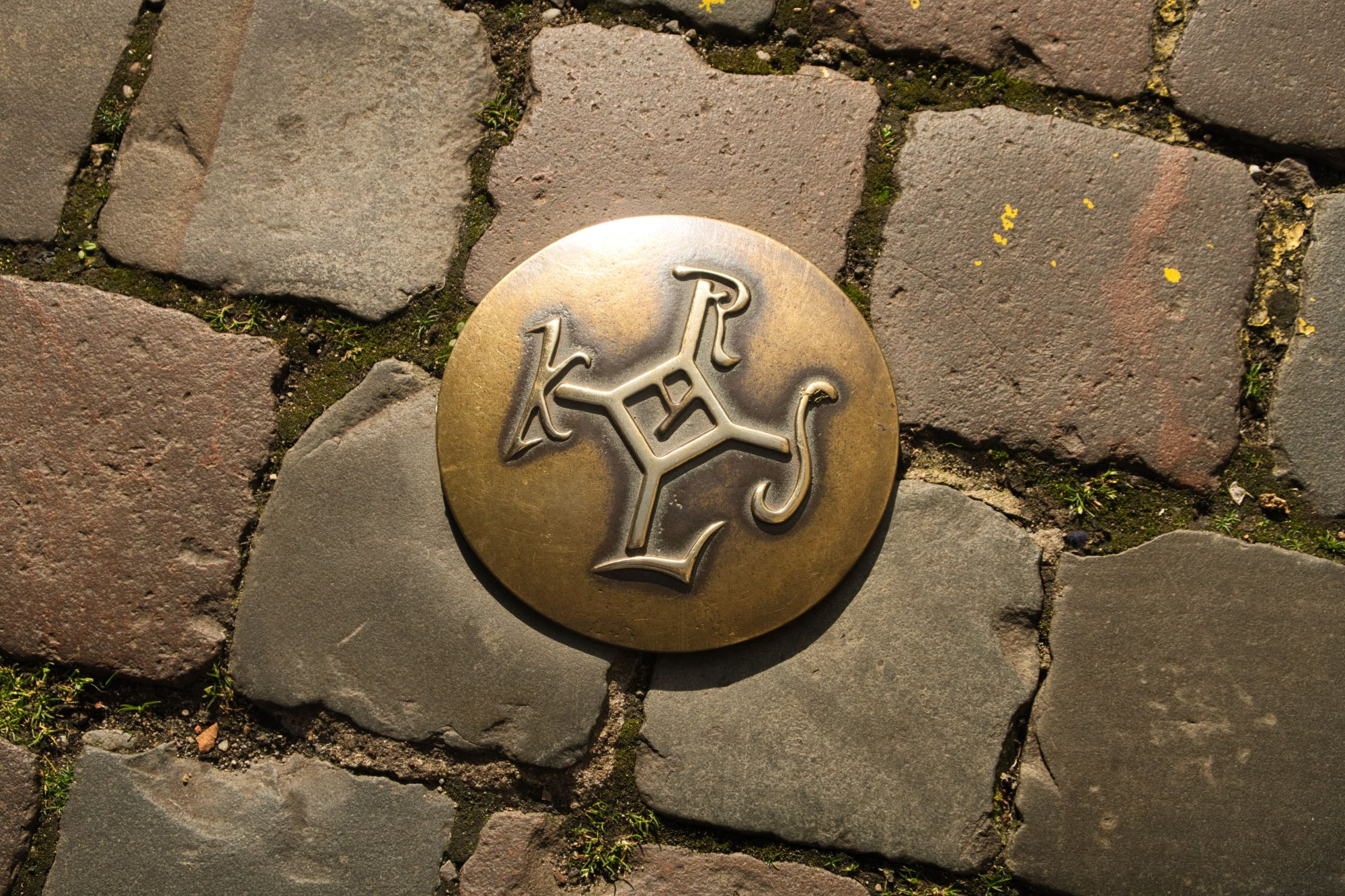 A bronze plate with embossed monogram of Charlemagne, set between the street cobbles in Aachen