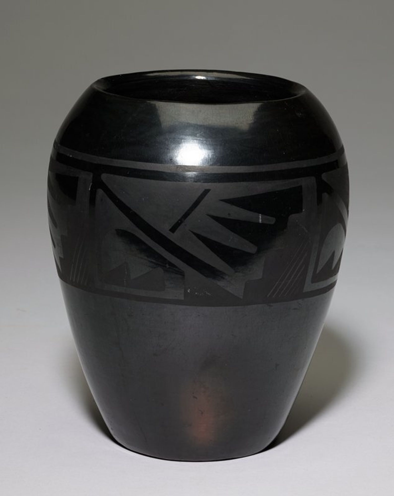 flat bottom; pot flares outward to shoulder, then inward to wide mouth; shiny black patina with band of dull black repeating designs (four repeats) with geometric forms including diagonals and zigzags