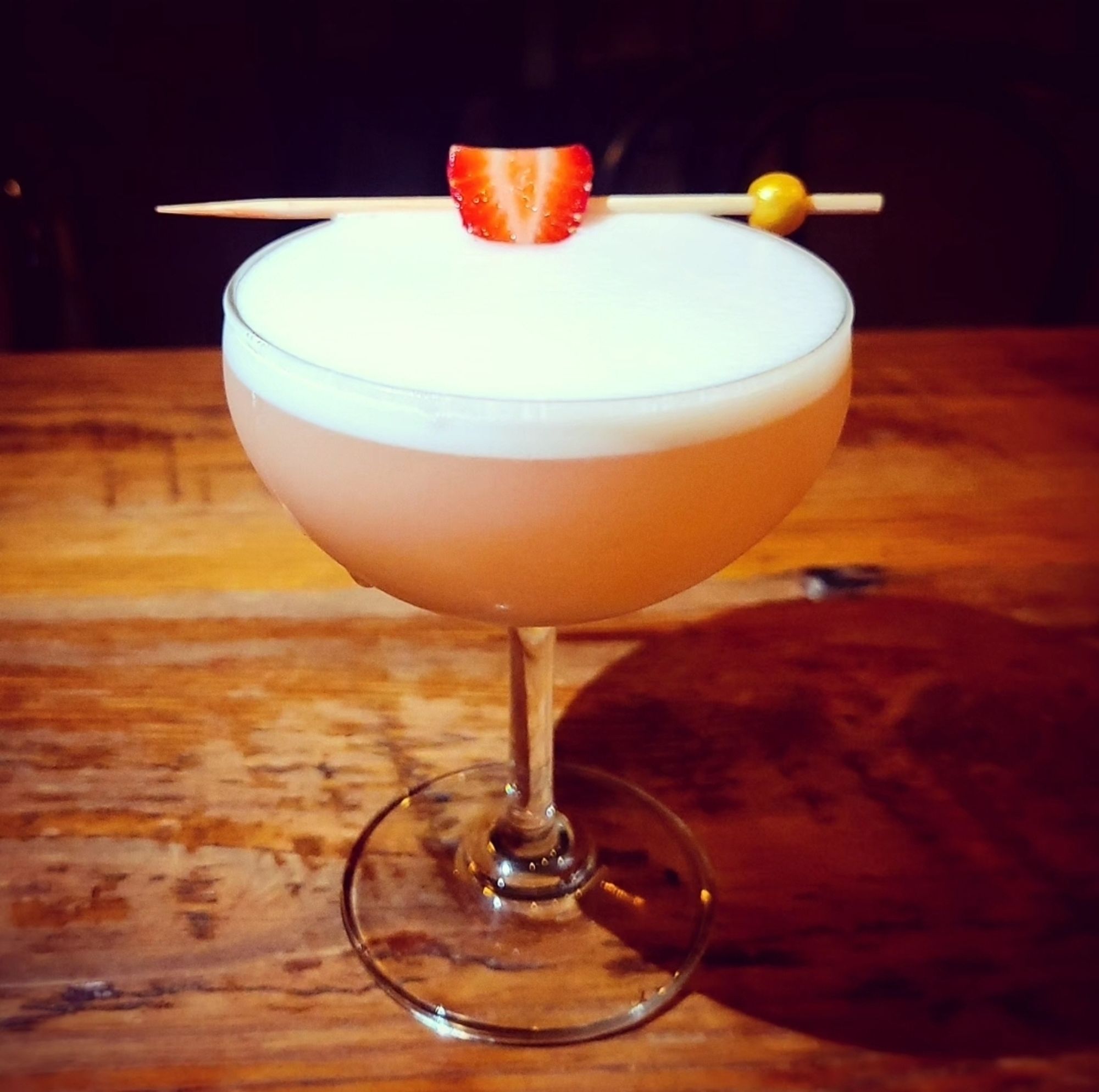 The described cocktail in a coupe glass, garnished with a strawberry slice