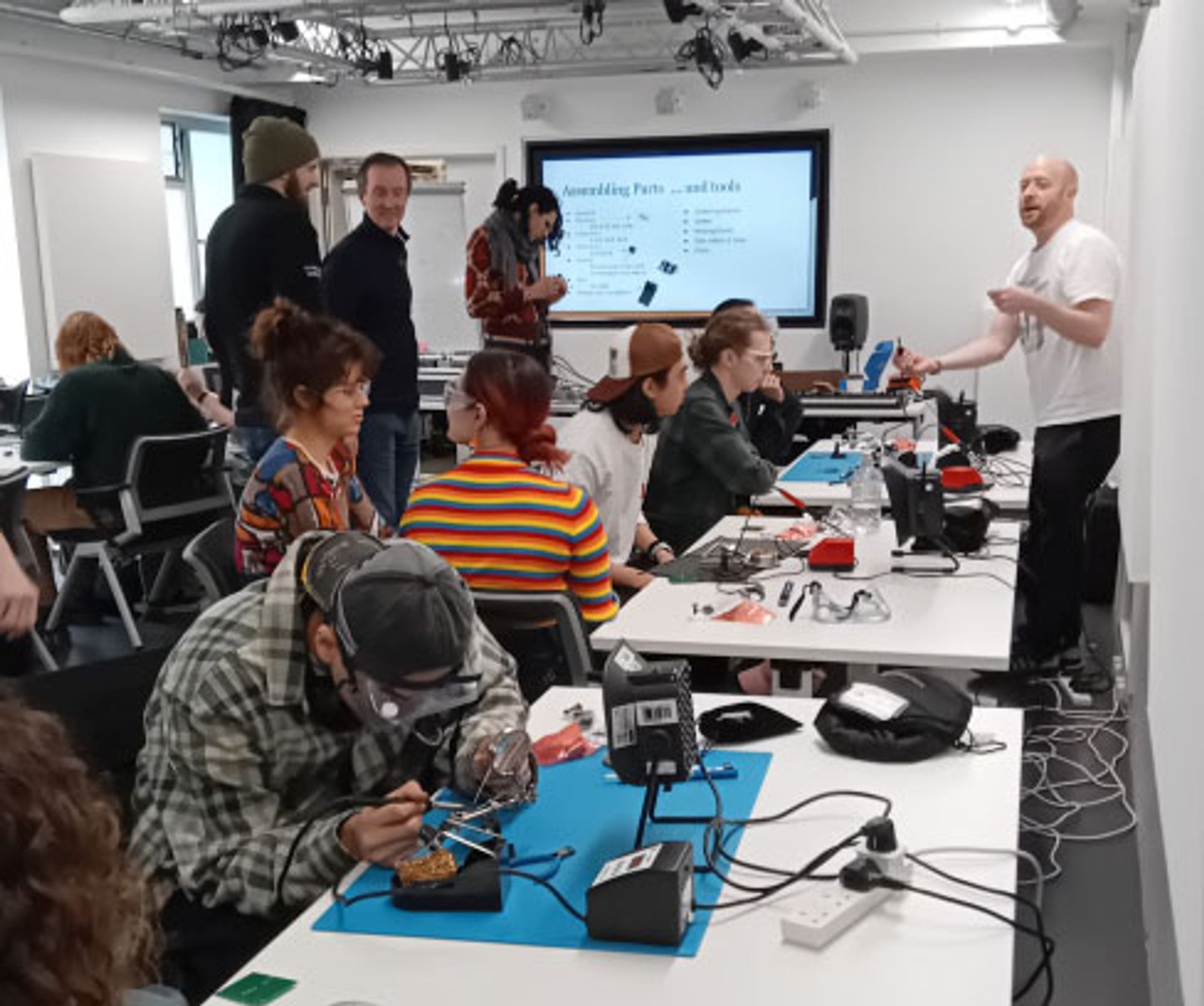 Students working with soldering irons and tech equipment