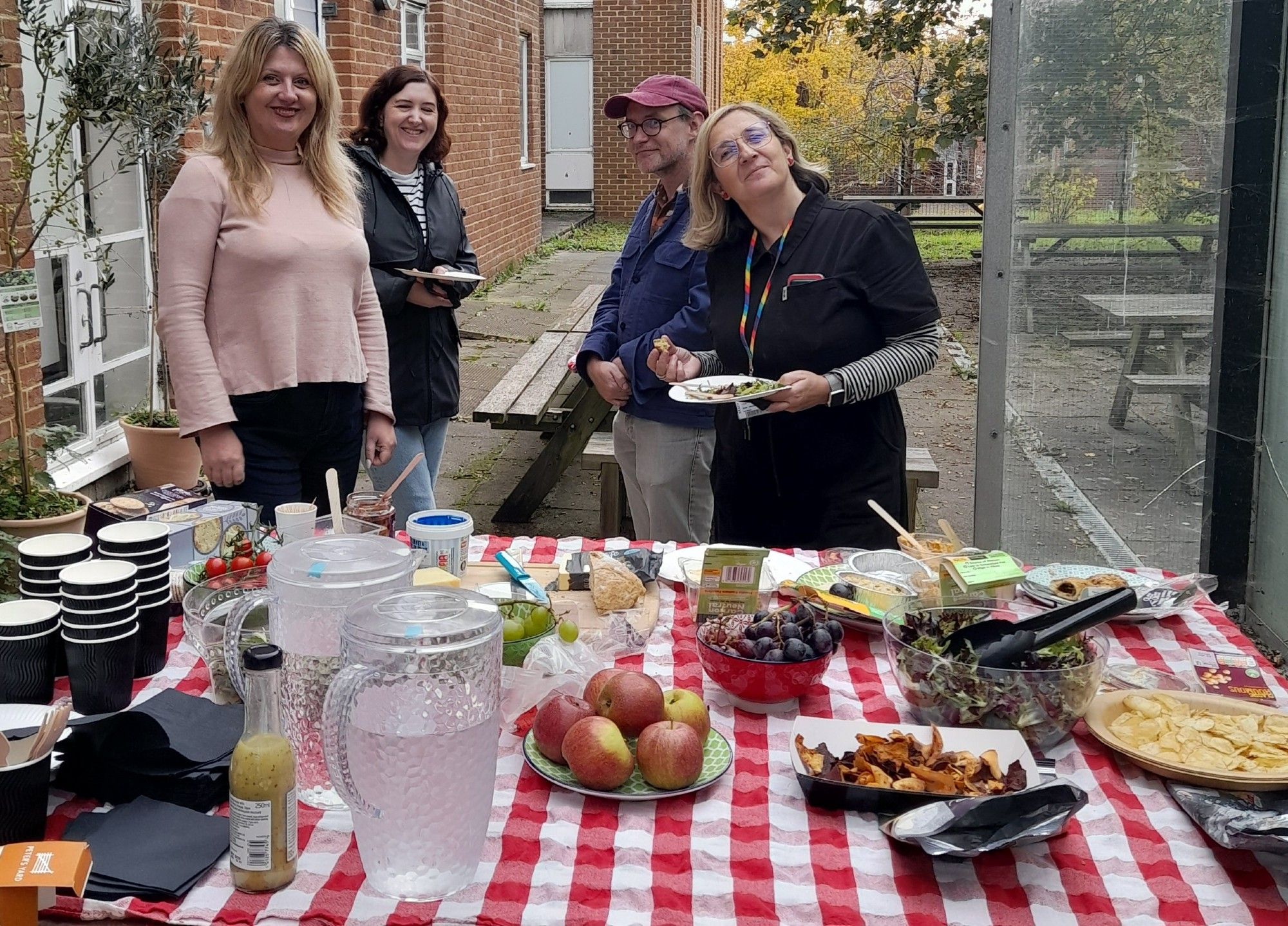 image of people in garden around picnic table with food