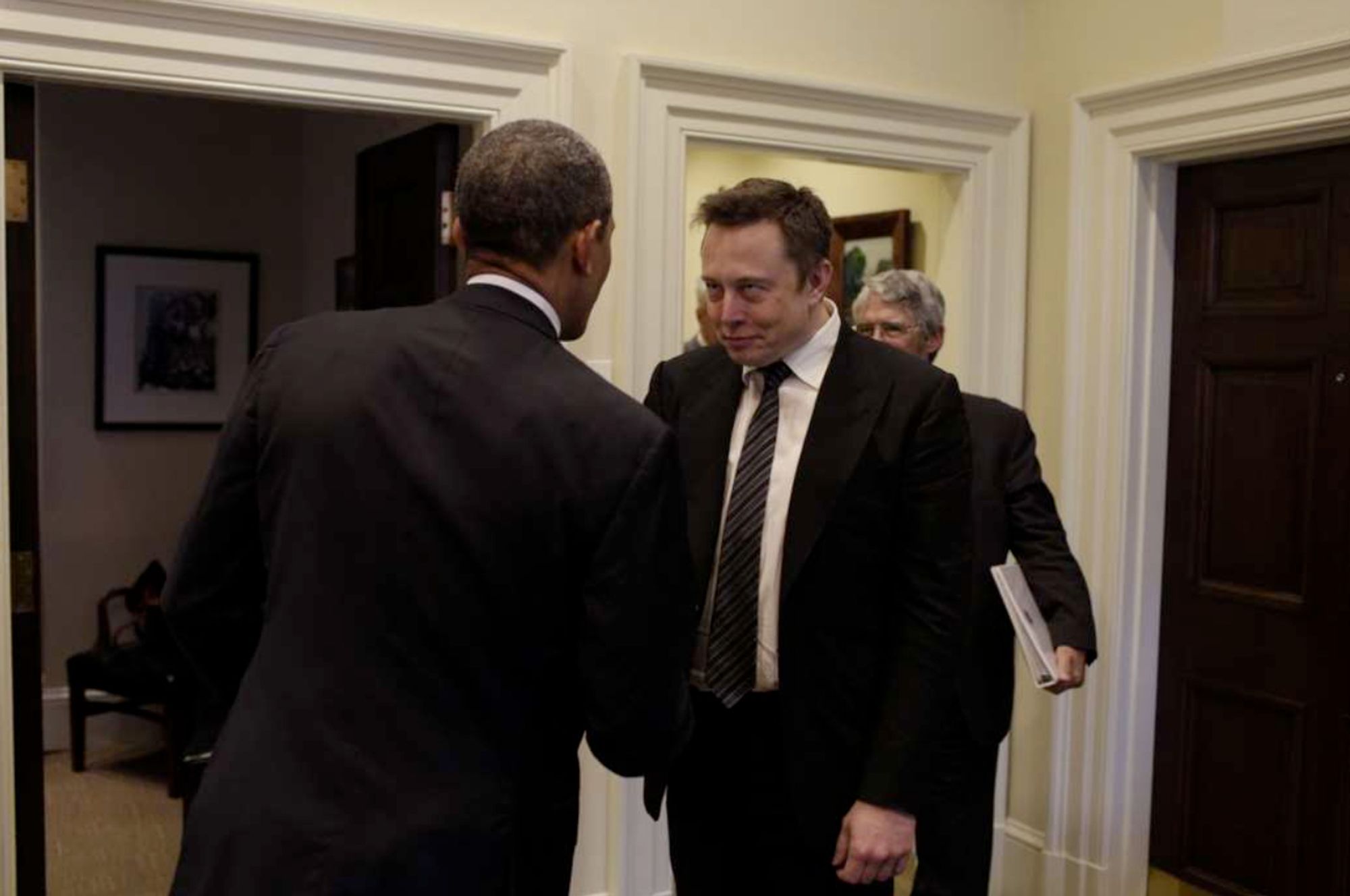 Elon Musk making a sinister face as he goes to shake Obama's hand