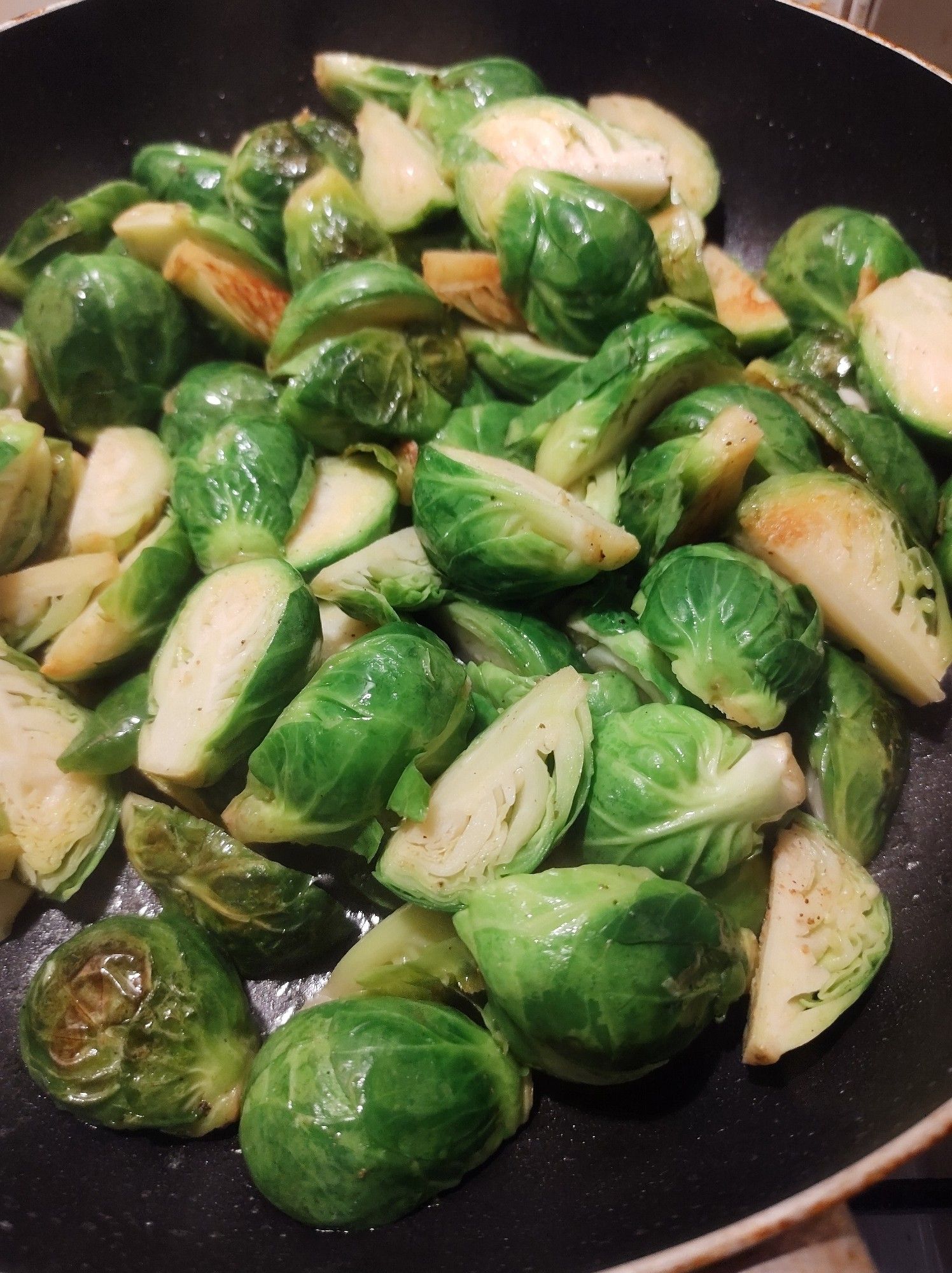 Veganes Rosenkohlgericht - Frischer Rosenkohl geviertelt brät in hoher Pfanne mit Salz und Pfeffer, Messerspitze Muskat und Kümmel